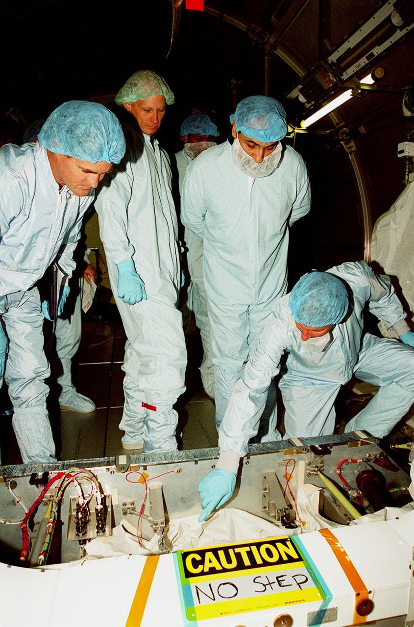 With workers at left looking on, STS-100 crew members check out equipment inside the Multi-Purpose Logistics Module Raffaello, located in the Space Station Processing Facility. At right is Commander Kent Rominger; to his left in the photo is Mission Specialist Umberto Guidoni, with the European Space Agency. Mission STS-100, scheduled to launch April 19, 2001, will include Raffaello as well as the Space Station Remote Manipulator System (SSRMS) as its payload. MPLMs are pressurized modules that will serve as the International Space Station's “moving vans,” carrying laboratory racks filled with equipment, experiments and supplies to and from the station aboard the Space Shuttle. The SSRMS is the primary means of transferring payloads between the orbiter payload bay and the International Space Station for assembly