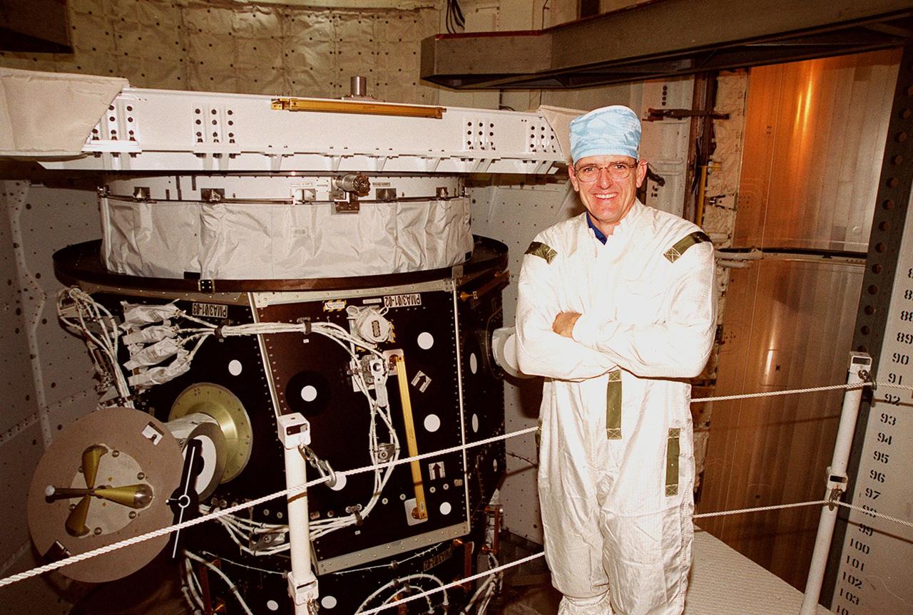 STS-92 Mission Specialist William S. McArthur Jr. smiles for the camera during inspection of the payload (left) in Space Shuttle Discovery’s payload bay. He and other crew members Commander Brian Duffy, Pilot Pamela Ann Melroy and Mission Specialists Koichi Wakata of Japan, Leroy Chiao, Peter J.K. “Jeff” Wisoff and Michael E. Lopez-Alegria are preparing for launch on Oct. 5, 2000. The mission is the fifth flight for the construction of the International Space Station. The payload includes the Integrated Truss Structure Z-1 and the third Pressurized Mating Adapter. During the 11-day mission, four extravehicular activities (EVAs), or space walks, are planned