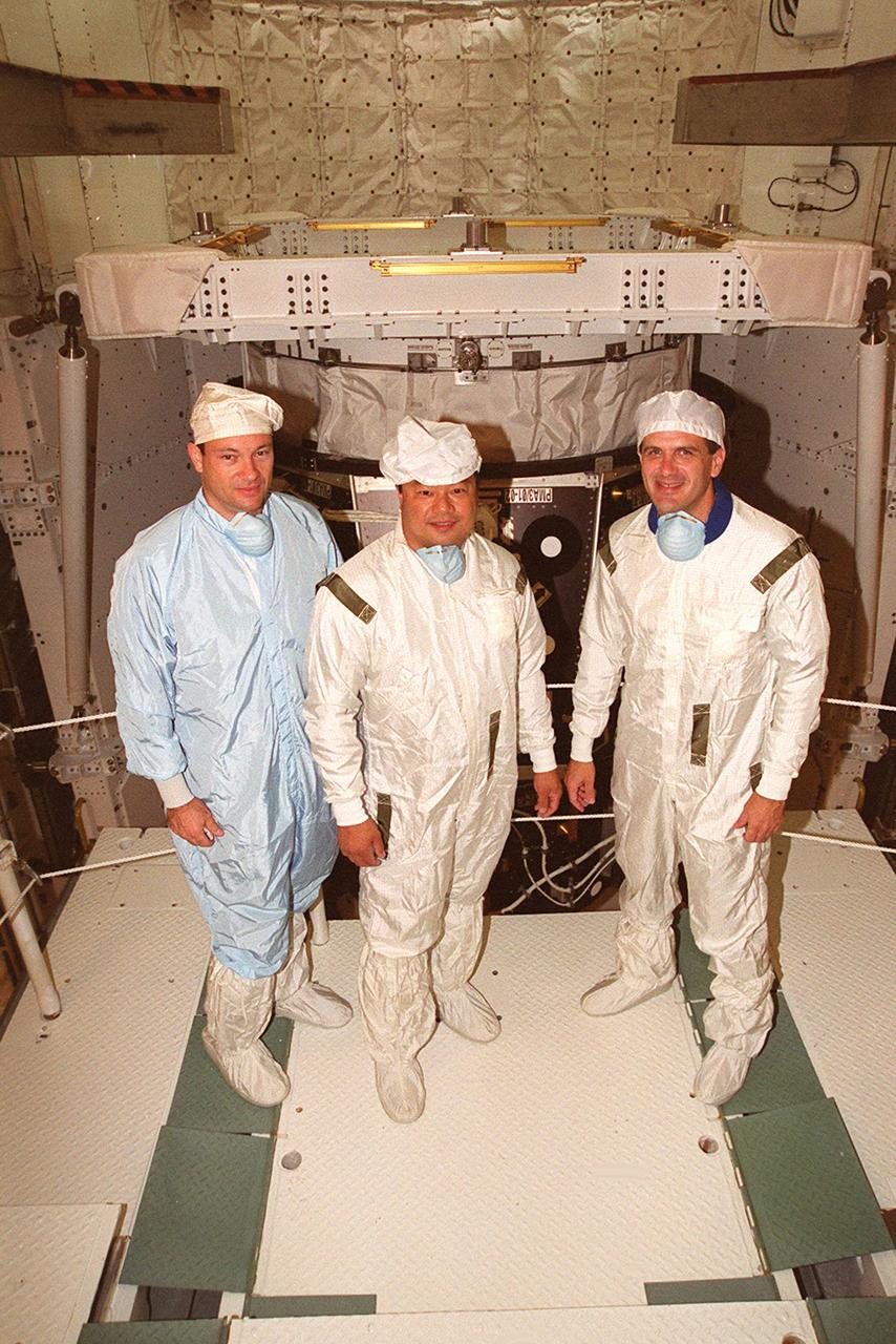KENNEDY SPACE CENTER, FLA. -- During inspection of the payload in Space Shuttle Discovery’s payload bay (background), STS-92 Mission Specialists Michael E. Lopez-Alegria, Leroy Chiao and Peter J.K. “Jeff” Wisoff pause for a photo. They and other crew members Commander Brian Duffy, Pilot Pamela Ann Melroy and Mission Specialists Koichi Wakata of Japan and William S. McArthur Jr. are preparing for launch on Oct. 5, 2000. The mission is the fifth flight for the construction of the International Space Station. The payload includes the Integrated Truss Structure Z-1 and the third Pressurized Mating Adapter. During the 11-day mission, four extravehicular activities (EVAs), or space walks, are planned