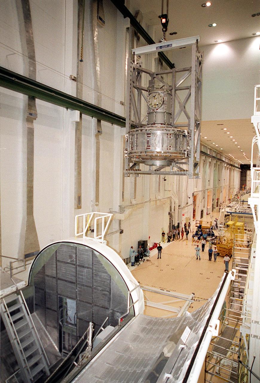 KENNEDY SPACE CENTER, FLA. -- In the Operations and Checkout Building, the Joint Airlock Module is carried across the Operations and Checkout Building toward a stand on the floor. The module will be moved to a horizontal position and placed in the payload canister at left. Then it will be taken to the Space Station Processing Facility where it will continue to undergo preflight processing for the STS-104 mission scheduled for launch aboard Space Shuttle Atlantis May 17, 2001. The Joint Airlock Module is the gateway from which crew members aboard the International Space Station will enter and exit the 470-ton orbiting research facility