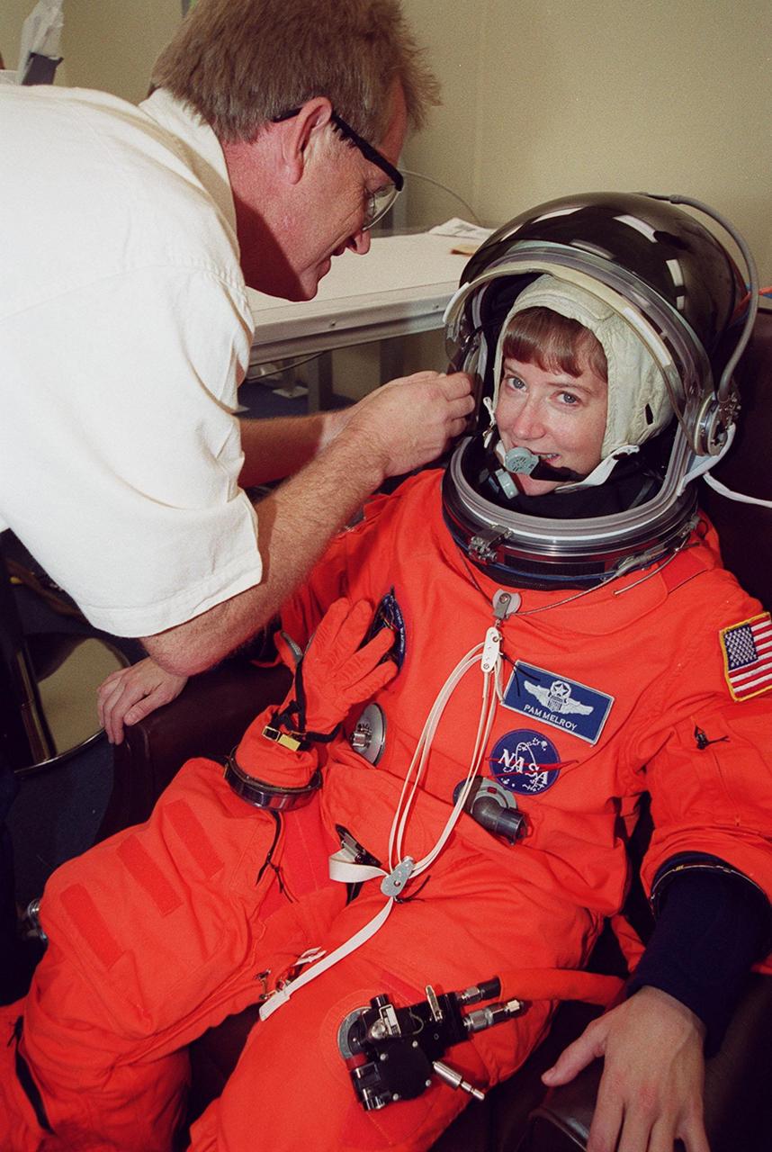 STS-92 Pilot Pamela Ann Melroy has her helmet checked during suitup for launch, scheduled for 8:05 p.m. EDT. The mission is the fifth flight for the construction of the ISS. The payload includes the Integrated Truss Structure Z-1 and the third Pressurized Mating Adapter. During the 11-day mission, four extravehicular activities (EVAs), or spacewalks, are planned. The Z-1 truss is the first of 10 that will become the backbone of the International Space Station, eventually stretching the length of a football field. PMA-3 will provide a Shuttle docking port for solar array installation on the sixth ISS flight and Lab installation on the seventh ISS flight. This launch is the first for Melroy. Landing is expected Oct. 21 at 3:55 p.m. EDT