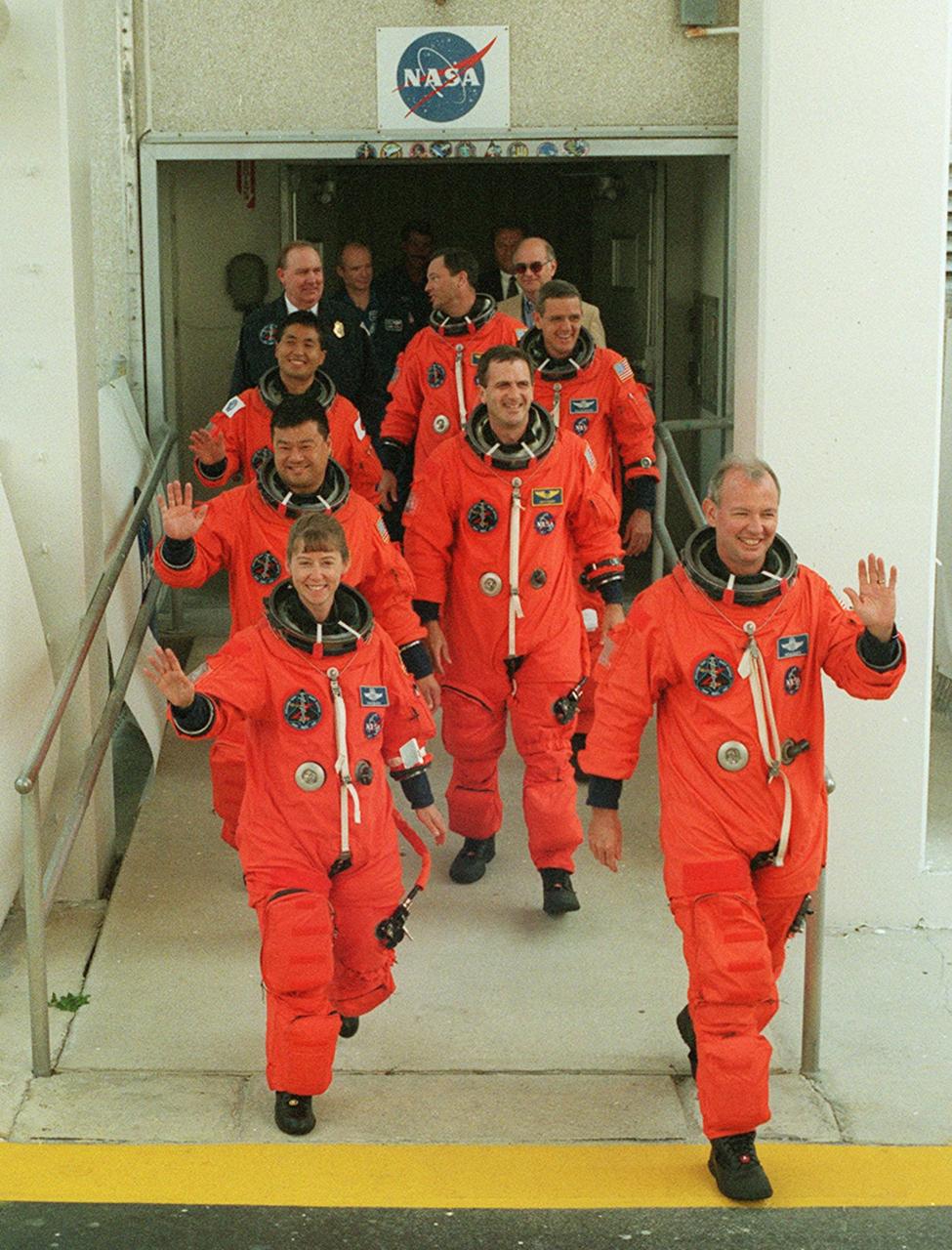 The STS-92 crew greets cheering onlookers as they exit the Operations and Checkout Building for the trip to Launch Pad 39A and liftoff of Space Shuttle Discovery. In rows of two, starting at front, are Pilot Pamela Ann Melroy and Commander Brian Duffy; Mission Specialists Leroy Chiao, Peter J.K. “Jeff” Wisoff; Koichi Wakata, William S. McArthur Jr.; and Michael E. Lopez-Alegria taking up the rear. . This launch is the fourth for Duffy and Wisoff, the third for Chiao and McArthur, second for Wakata and Lopez-Alegria, and first for Melroy. During the 11-day mission to the International Space Station, four extravehicular activities (EVAs), or spacewalks, are planned for construction. The payload includes the Integrated Truss Structure Z-1 and the third Pressurized Mating Adapter. The Z-1 truss is the first of 10 that will become the backbone of the Space Station, eventually stretching the length of a football field. PMA-3 will provide a Shuttle docking port for solar array installation on the sixth Station flight and Lab installation on the seventh Station flight. Launch is scheduled for 7:17 p.m. EDT. Discovery’s landing is expected Oct. 22 at 2:10 p.m. EDT