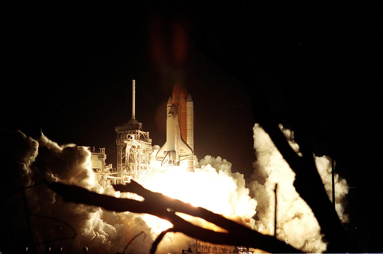 KENNEDY SPACE CENTER, Fla. -- Framed in angle of two tree branches, Space Shuttle Discovery appears to rise out of the smoke and steam at Launch Pad 39A. The perfect on-time liftoff at 7:17 p.m. EDT sends a crew of seven on a construction flight to the International Space Station on mission STS-92, the 100th in the history of the Shuttle program. Discovery also carries a payload that includes the Integrated Truss Structure Z-1, first of 10 trusses that will form the backbone of the Space Station, and the third Pressurized Mating Adapter that will provide a Shuttle docking port for solar array installation on the sixth Station flight and Lab installation on the seventh Station flight. Discovery’s landing is expected Oct. 22 at 2:10 p.m. EDT
