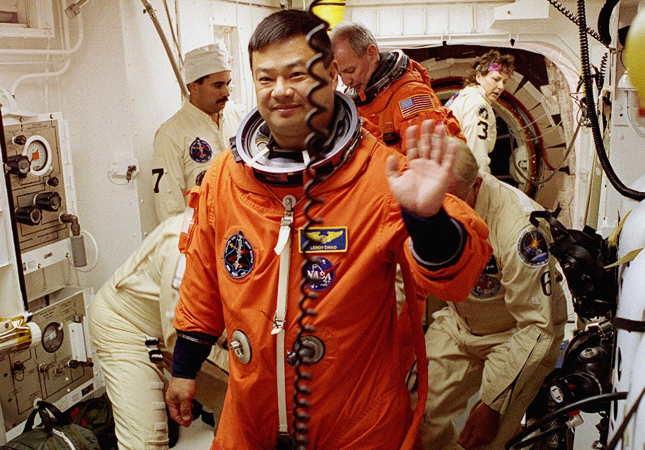 STS-92 Mission Specialist Leroy Chiao waves while waiting for suit check in the White Room. Behind him is Commander Brian Duffy. The White Room is an environmentally controlled area at the end of the Orbiter Access Arm that provides entry to the orbiter as well as emergency egress if needed. The arm remains in the extended position until 7 minutes 24 seconds before launch. Chiao, Duffy and the rest of the crew are undertaking the fifth flight to the International Space Station for construction. Discovery carries a payload that includes the Integrated Truss Structure Z-1, first of 10 trusses that will form the backbone of the Space Station, and the third Pressurized Mating Adapter that will provide a Shuttle docking port for solar array installation on the sixth Station flight and Lab installation on the seventh Station flight. The mission includes four spacewalks for the construction activities. Discovery’s landing is expected Oct. 22 at 2:10 p.m. EDT