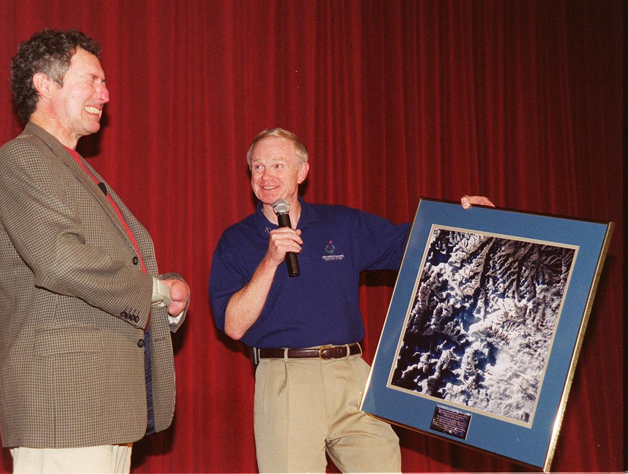 During Super Safety and Health Day at KSC, keynote speaker Dr. Beck Weathers grimaces over the satellite photo of Mt. Everest being presented by Center Director Roy Bridges. Weathers spoke about his ordeal of surviving the 1996 Mt. Everest disaster and the lessons learned from the experience. Safety Day is a full day of NASA-sponsored, KSC and 45th Space Wing events involving a number of health and safety related activities: Displays, vendors, technical paper sessions, panel discussions, a keynote speaker, etc. The entire Center and Wing stand down to participate in the planned events. Safety Day is held annually to proactively increase awareness in safety and health among the government and contractor workforce population. The first guiding principle at KSC is “Safety and Health First.” KSC’s number one goal is to “Assure sound, safe and efficient practices and processes are in place for privatized/commercialized launch site processing.