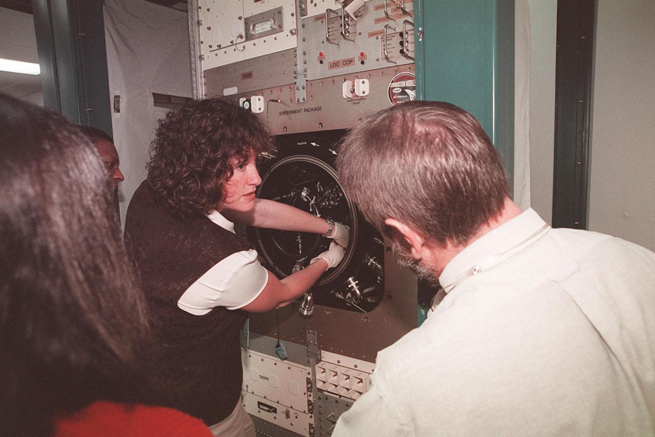 KENNEDY SPACE CENTER, FLA. -- At SPACEHAB, STS-107 Mission Specialist Laurel Clark gets hands-on experience with equipment that will be on the mission. Watching in the left foreground is Mission Specialist Kalpana Chawla; next to her at left is Mission Specialist Michael Anderson. Identified as a research mission, STS-107 is scheduled for launch July 19, 2001
