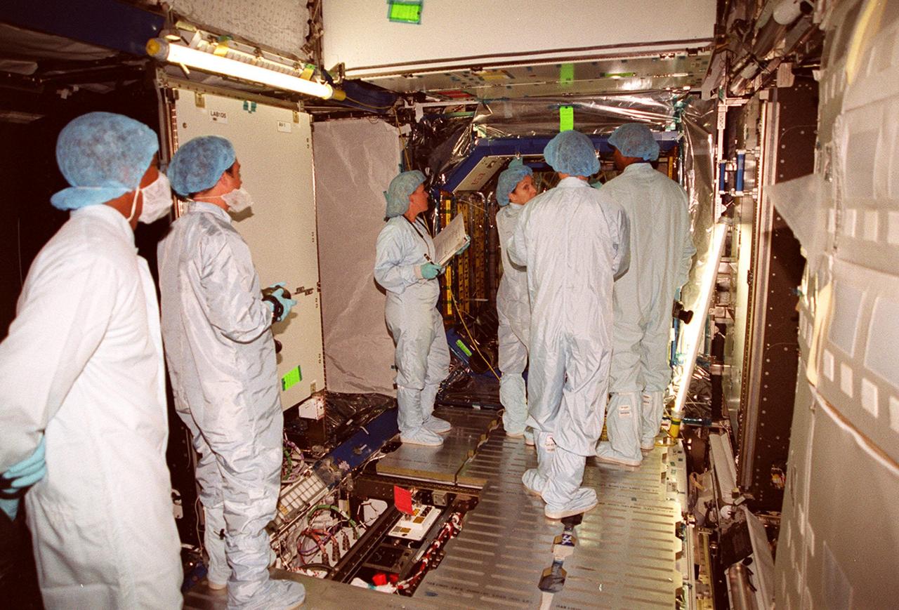 In the Space Station Processing Facility, members of the STS-98 crew check out equipment in the U.S. Lab, Destiny, with the help of workers. In the background, looking over her shoulder, is Mission Specialist Marsha Ivins. Others in the crew are Commander Ken Cockrell, Pilot Mark Polansky and Mission Specialists Robert Curbeam and Thomas Jones. The crew is taking part in Crew Equipment Interface Test activities, becoming familiar with equipment it will be handling during the mission. The mission will be transporting the Lab to the International Space Station with five system racks already installed inside of the module. With delivery of electronics in the lab, electrically powered attitude control for Control Moment Gyroscopes will be activated. The STS-98 launch is scheduled for Jan. 18, 2001