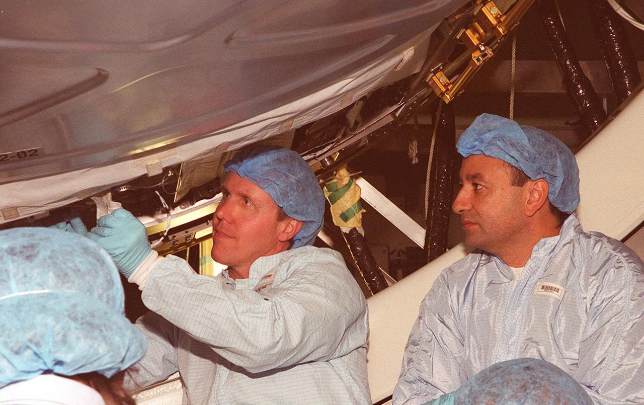 In the Space Station Processing Facility, STS-98 Mission Specialist Thomas Jones works on a part of the U.S. Lab, Destiny. Watching at right is Pilot Mark Polansky. Jones and Polansky, along with other crew members, are taking part in Crew Equipment Interface Test activities to become familiar with equipment they will be handling during the mission. Others in the crew are Commander Ken Cockrell and Mission Specialists Robert Curbeam and Marsha Ivins. The mission will be transporting the Lab to the International Space Station with five system racks already installed inside of the module. With delivery of electronics in the lab, electrically powered attitude control for Control Moment Gyroscopes will be activated. The STS-98 launch is scheduled for Jan. 18, 2001
