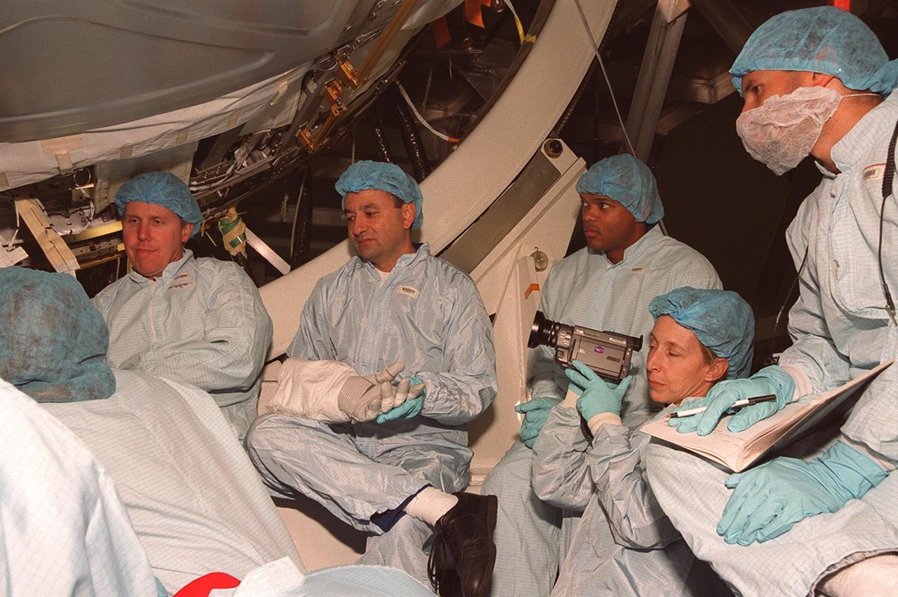 In the Space Station Processing Facility, members of the STS-98 crew, sitting in front of the U.S. Lab, Destiny, listen to a trainer during Crew Equipment Interface Test (CEIT) activities. Seen, left to right, are Mission Specialist Thomas Jones, Pilot Mark Polansky and Mission Specialists Robert Curbeam and Marsha Ivins (with camera). The CEIT allows a crew to become familiar with equipment they will be handling during the mission. With launch scheduled for Jan. 18, 2001, the STS-98 mission will be transporting the Lab to the International Space Station with five system racks already installed inside of the module. After delivery of electronics in the lab, electrically powered attitude control for Control Moment Gyroscopes will be activated