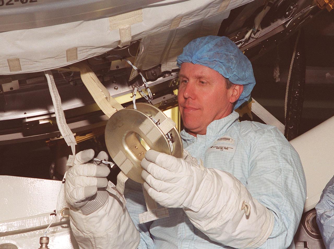 STS-98 Mission Specialist Thomas Jones practices handling a piece of equipment on the U.S. Lab, Destiny, while wearing the gloves he will wear in space. Jones and other crew members are taking part in Crew Equipment Interface Test activities to become familiar with equipment they will be handling during the mission. With launch scheduled for Jan. 18, 2001, the STS-98 mission will be transporting the Lab to the International Space Station with five system racks already installed inside of the module. After delivery of electronics in the lab, electrically powered attitude control for Control Moment Gyroscopes will be activated