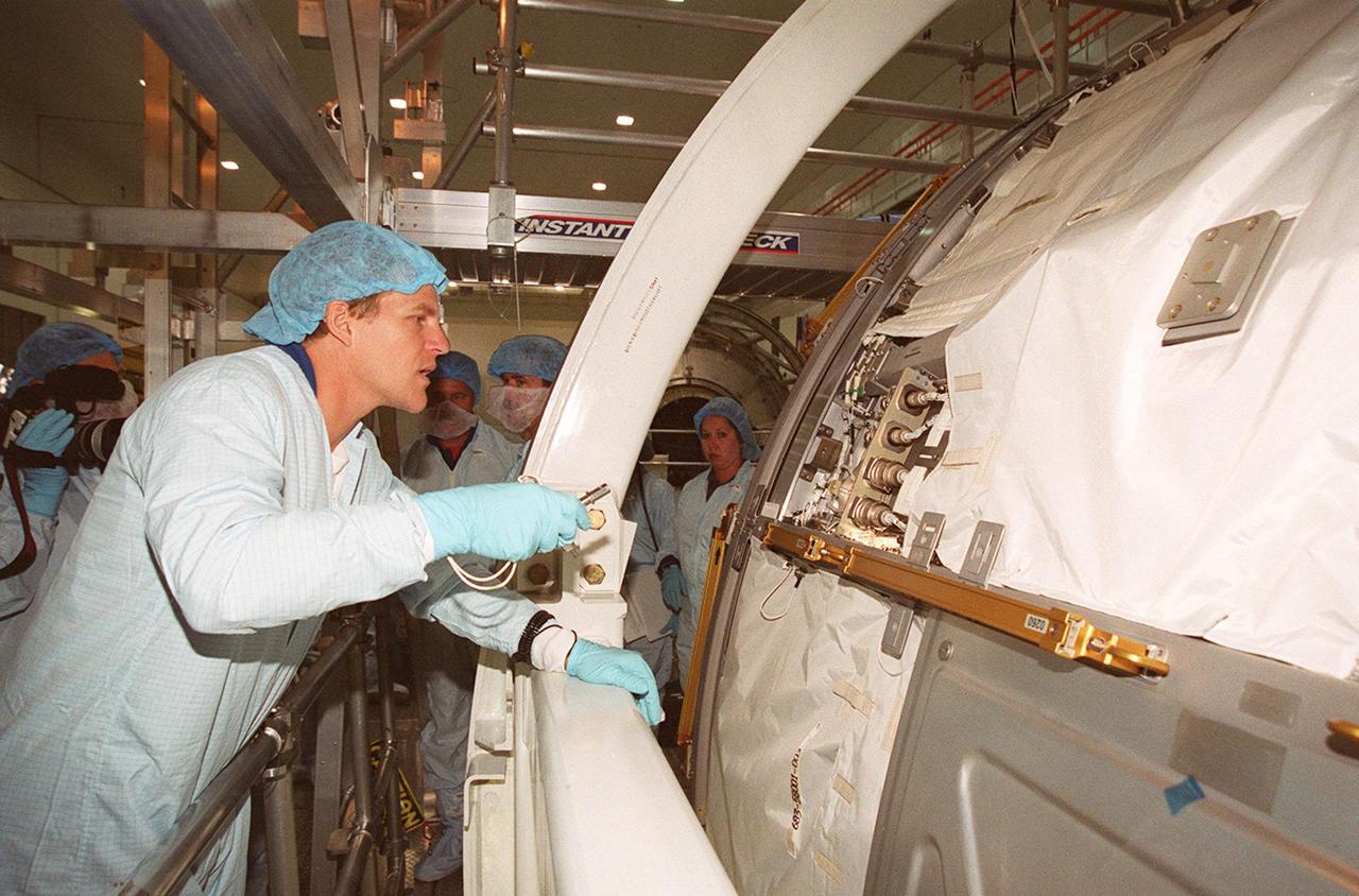 In the Space Station Processing Facility, STS-100 Mission Specialist Scott Parazynski looks over part of the U.S. Lab, Destiny. Mission STS-100 will be the ninth construction flight for the International Space Station. It is scheduled to launch April 19, 2001