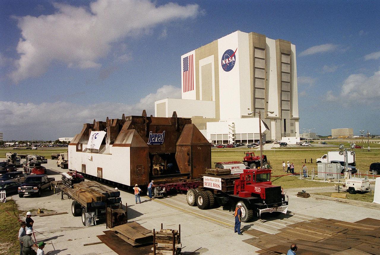 A launch table fabricated by Jered Industries in Georgia waits for transfer to Launch Complex 37B, Cape Canaveral Air Force Station, after being moved off the barge that brought it to the turn basin in KSC’s Launch Complex 39 Area. In the background is the Vehicle Assembly Building. The table was built in support of the Delta Evolved Expendable Launch Vehicle (EELV) program, known as Delta IV. It was floated on the barge down the Intercoastal Waterway, through the Barge Canal to the turn basin. The table is approximately 70 feet long, 40 feet wide and 50 feet high, and weighs about 600,000 pounds. Accompanying the launch table on the barge are flame deflectors, which are also to be erected on pad 37B