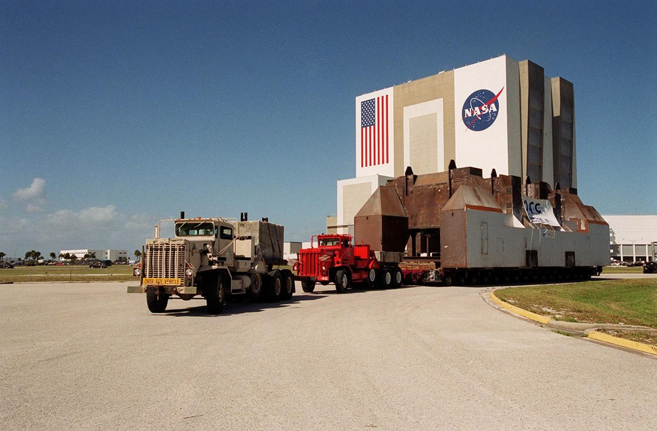 A launch table, fabricated by Jered Industries in Georgia for Boeing, turns the corner away from the barge that brought it to the turn basin in KSC’s Launch Complex 39 Area. In the background is the Vehicle Assembly Building. The table was built in support of the Delta Evolved Expendable Launch Vehicle (EELV) program, known as Delta IV. It was floated on the barge down the Intercoastal Waterway, through the Barge Canal to the turn basin. The table, whcih is approximately 70 feet long, 40 feet wide and 50 feet high, weighing about 600,000 pounds, is being transferred to Launch Complex 37B, Cape Canaveral Air Force Station. Accompanying the launch table on the barge are flame deflectors, which are also to be erected on pad 37B