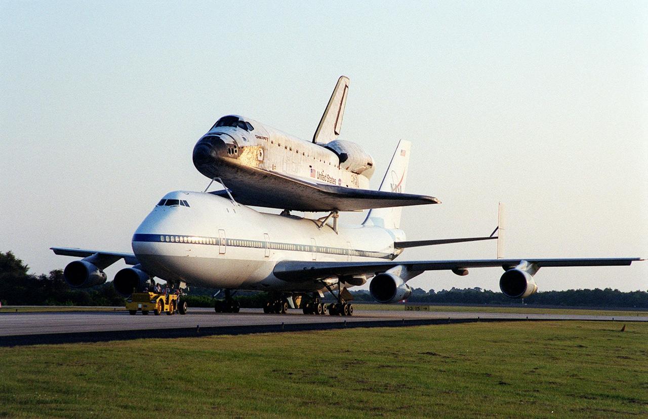 After landing at the Shuttle Landing Facility (SLF), the Shuttle Carrier Aircraft (SCA), with its unique cargo Discovery on top, is towed to the mate/demate device at the SLF. Discovery will be lifted off the SCA and transported to the Orbiter Processing Facility bay 1. There it will undergo preparations for its next launch, STS-102, scheduled for February 2001