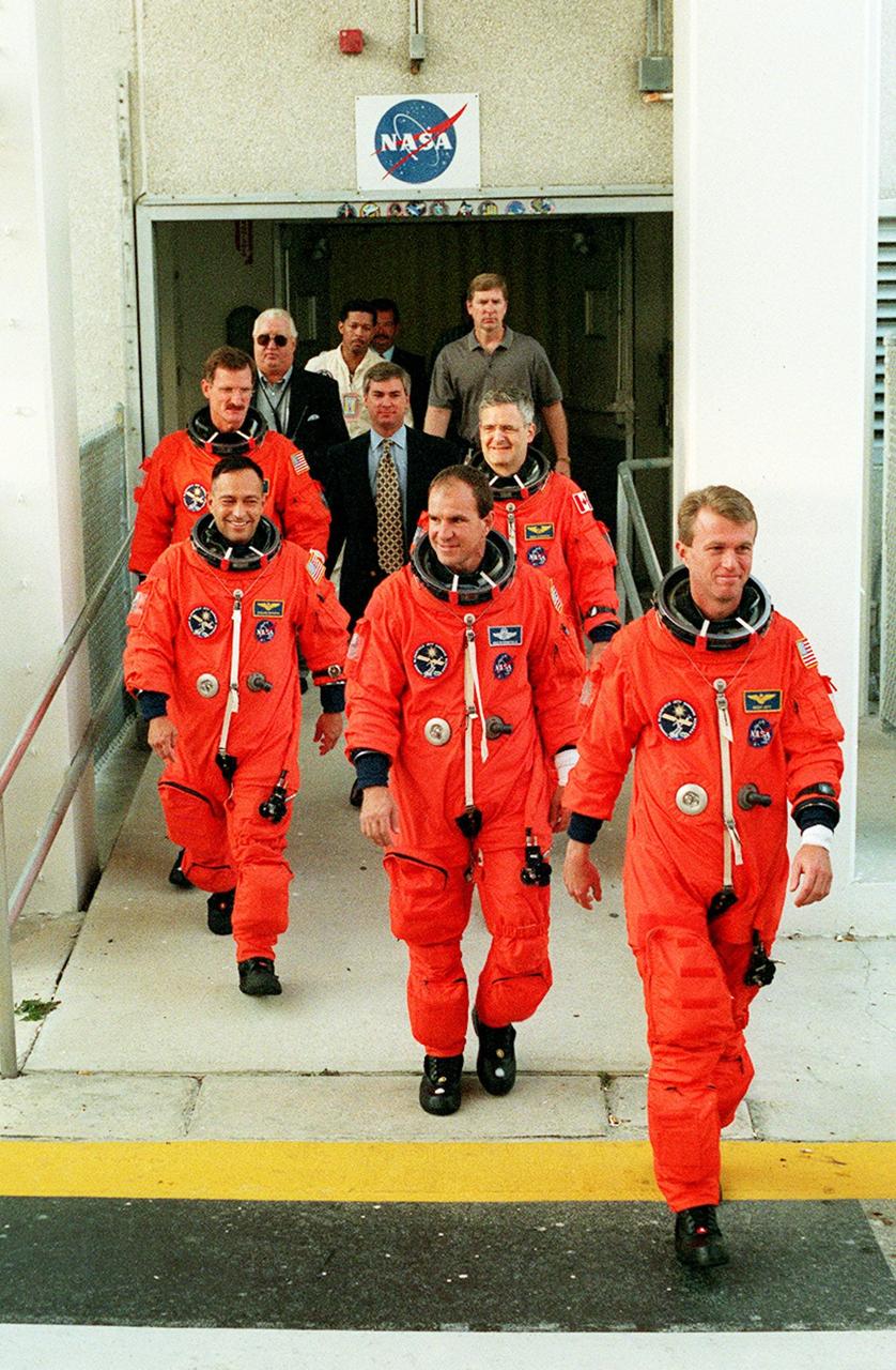 The STS-97 crew get a taste of the excitement of launch day as they exit the O&C Building to head for Launch Pad 39B. They are taking part in Terminal Countdown Demonstration Test (TCDT) activities that include emergency egress training and a simulated launch countdown. On the left (front to back) are Mission Specialists Carlos Noriega and Joe Tanner; on the right (front to back) are Commander Brent Jett, Pilot Mike Bloomfield and Mission Specialist Marc Garneau, who is a Canadian astronaut. Mission STS-97is the sixth construction flight to the International Space Station. Its payload includes the P6 Integrated Truss Structure and a photovoltaic (PV) module, with giant solar arrays that will provide power to the Station. The mission includes two spacewalks to complete the solar array connections. STS-97 is scheduled to launch Nov. 30 at 10:05 p.m. EST