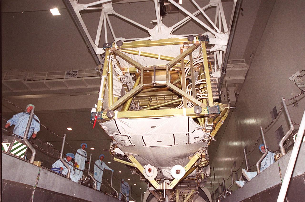 KENNEDY SPACE CENTER, FLA. -- Workers in the Space Station Processing Facility line up on the sides of the payload transport canister as an overhead crane moves the P6 integrated truss segment into position above it. After being placed in the canister, the truss will be transported to Launch Pad 39B and the payload changeout room. Then it will be moved into Space Shuttle Endeavour’s payload bay for mission STS-97. The P6 comprises Solar Array Wing-3 and the Integrated Electronic Assembly, to be installed on the Space Station. The Station’s electrical power system will use eight photovoltaic solar arrays, each 112 feet long by 39 feet wide, to convert sunlight to electricity. The solar arrays are mounted on a “blanket” that can be folded like an accordion for delivery. Once in orbit, astronauts will deploy the blankets to their full size. Gimbals will be used to rotate the arrays so that they will face the Sun to provide maximum power to the Space Station. The STS-97 launch is scheduled Nov. 30 at 10:06 p.m. EST