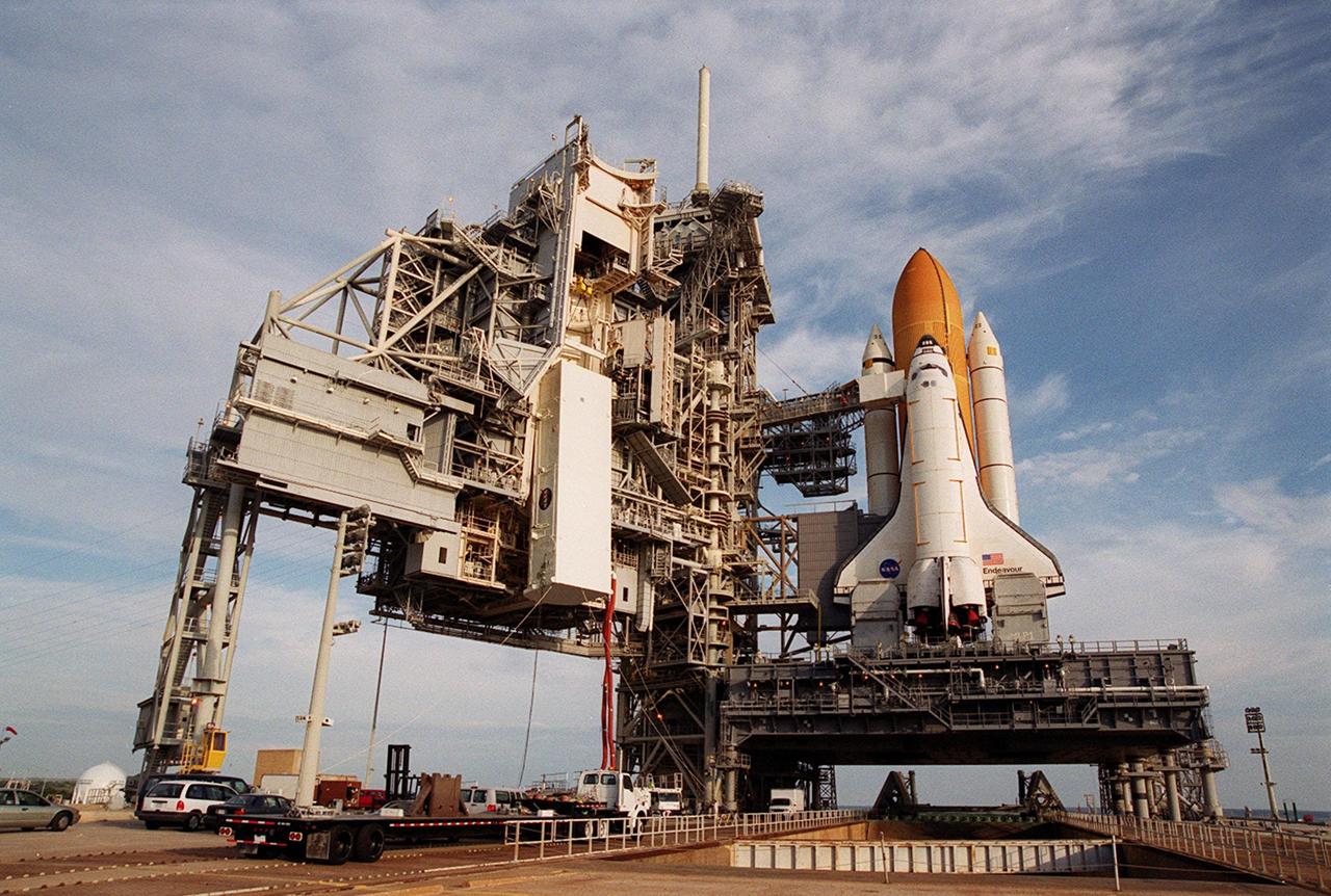 KENNEDY SPACE CENTER, FLA. -- The payload transport canister, with the P6 integrated truss segment inside, is close to the payload changeout room on the Rotating Service Structure (RSS) at left. The PCR is the enclosed, environmentally controlled portion of the RSS that supports payload delivery at the pad. At right is Space Shuttle Endeavour with its orange external tank and one solid rocket booster showing behind it. When the RSS is closed around Endeavour, the P6 truss will be moved into the orbiter’s payload bay. The P6, payload on mission STS-97, comprises Solar Array Wing-3 and the Integrated Electronic Assembly, to be installed on the International Space Station. The Station’s electrical power system will use eight photovoltaic solar arrays, each 112 feet long by 39 feet wide, to convert sunlight to electricity. The solar arrays are mounted on a “blanket” that can be folded like an accordion for delivery. Once in orbit, astronauts will deploy the blankets to their full size. Gimbals will be used to rotate the arrays so that they will face the Sun to provide maximum power to the Space Station. Launch of STS-97 is scheduled for Nov. 30 at 10:06 p.m. EST