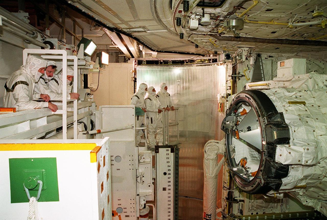 Members of the STS-97 crew look into Endeavour’s payload bay at some of the equipment that will be carried on the mission. At far left are (left to right) Commander Brent Jett and Mission Specialist Joseph Tanner, with a technician. At center are Mission Specialists Marc Garneau and Carlos Noriega, plus Pilot Michael Bloomfield. The equipment visible at right are the orbiter docking system (ODS) (center) and Canadian robotic arm (left and below the ODS). The arm will be used during spacewalks on the mission to install solar arrays. Each more than 100 feet long, the arrays will capture energy from the sun and convert it to power for the Station. STS-97 is scheduled to launch Nov. 30 at about 10:06 p.m. EST