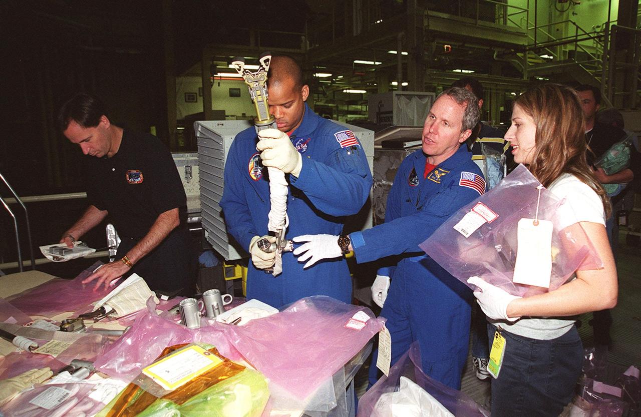 KENNEDY SPACE CENTER, FLA. -- In the Orbiter Processing Facility, STS-98 Mission Specialists Robert Curbeam (center left) and Tom Jones (center right) practice with tools that will be used on extravehicular activities on their mission. The STS-98 crew is at KSC for Crew Equipment Interface Test activities. Launch on mission STS-98 is scheduled for Jan. 18, 2001. It will be transporting the U.S. Lab, Destiny, to the International Space Station with five system racks already installed inside of the module. After delivery of electronics in the lab, electrically powered attitude control for Control Moment Gyroscopes will be activated