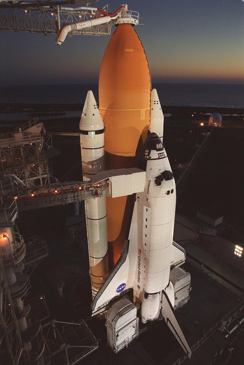 As dawn breaks on the horizon, Space Shuttle Endeavour is seen standing ready for launch, targeted for 10:06 p.m. EST tonight on mission STS-97 to the International Space Station. The Rotating Service Structure was rolled back just before dawn. On top of the orange external tank is the Gaseous Oxygen Vent Arm and its vent hood, known as the “beanie cap.” The hood is raised to clear the external tank 2.5 minutes before launch. The orbiter carries the P6 Integrated Truss Segment containing solar arrays that will be temporarily installed to the Unity connecting module by the Z1 truss, recently delivered to and installed on the Station on mission STS-92. The two solar arrays are each more than 100 feet long. They will capture energy from the sun and convert it to power for the Station. Two spacewalks will be required to install the solar array connections