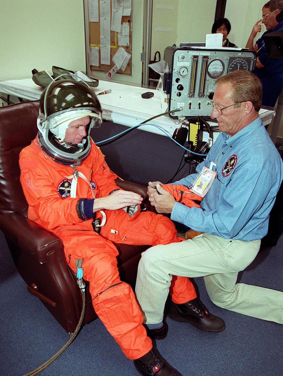 With the help of a suit technician, STS-97 Commander Brent Jett dons his launch and entry suit. This is his third Shuttle flight.; Mission STS-97 is the sixth construction flight to the International Space Station. It is transporting the P6 Integrated Truss Structure that comprises Solar Array Wing-3 and the Integrated Electronic Assembly, to be installed on the Space Station. The solar arrays are mounted on a “blanket” that can be folded like an accordion for delivery. Once in orbit, astronauts will deploy the blankets to their full size. The 11-day mission includes two spacewalks to complete the solar array connections. The Station’s electrical power system will use eight photovoltaic solar arrays, each 112 feet long by 39 feet wide, to convert sunlight to electricity. Gimbals will be used to rotate the arrays so that they will face the Sun to provide maximum power to the Space Station. Launch is scheduled for Nov. 30 at 10:06 p.m. EST