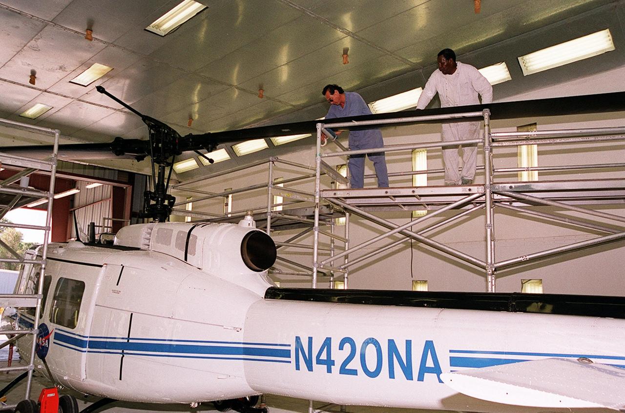 KENNEDY SPACE CENTER, FLA. -- Workers paint the blades of a NASA UH-1H helicopter, changing the black to a pattern of white and yellow stripes. The pattern provides better visibility in smoke and fire conditions. When the rotors are turning, the stripes create a yellow and white circle that is more easily seen by a second helicopter from above. The helicopters, primarily used for security and medical evacuation for NASA, will be used to deliver water via buckets during brush fires. The change was made to comply with U.S. Fish and Wildlife and Department of Forestry regulations for helicopter-assisted fire control