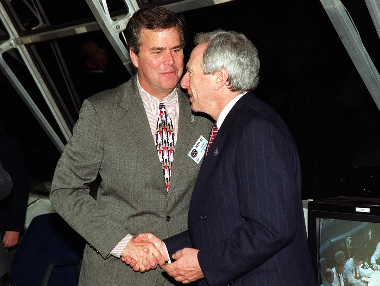 KENNEDY SPACE CENTER, FLA. -- In the Firing Room, Launch Control Center, after a successful launch of Space Shuttle Endeavour on mission STS-97, Florida Governor Jeb Bush shakes the hand of NASA Administrator Daniel Goldin. Liftoff of Endeavour occurred at 10:06:01 p.m. Endeavour and its five-member crew will deliver U.S. solar arrays to the International Space Station and be the first Shuttle crew to visit the Station’s first resident crew. The 11-day mission includes three spacewalks. This marks the 101st mission in Space Shuttle history and the 25th night launch. Endeavour is expected to land at KSC Dec. 11 at 6:19 p.m. EST