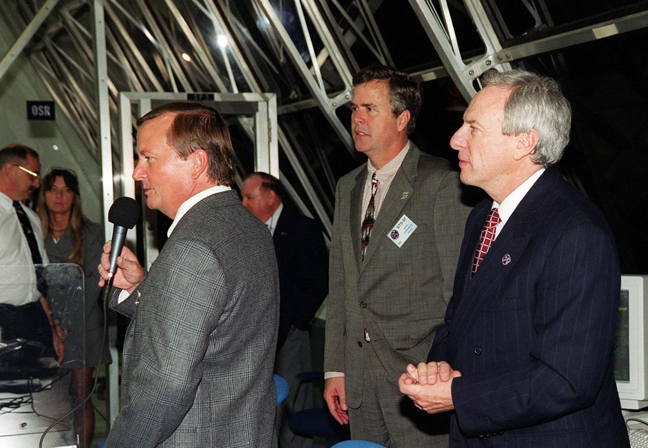 KENNEDY SPACE CENTER, FLA. -- In the Firing Room, Launch Control Center, after a successful launch of Space Shuttle Endeavour on mission STS-97, Launch Director Michael Leinbach (with microphone) addresses the launch team. Behind him at right are Florida Governor Jeb Bush and NASA Administrator Daniel Goldin. Liftoff of Endeavour occurred at 10:06:01 p.m. EST. Endeavour and its five-member crew will deliver U.S. solar arrays to the International Space Station and be the first Shuttle crew to visit the Station’s first resident crew. The 11-day mission includes three spacewalks. This marks the 101st mission in Space Shuttle history and the 25th night launch. Endeavour is expected to land at KSC Dec. 11 at 6:19 p.m. EST