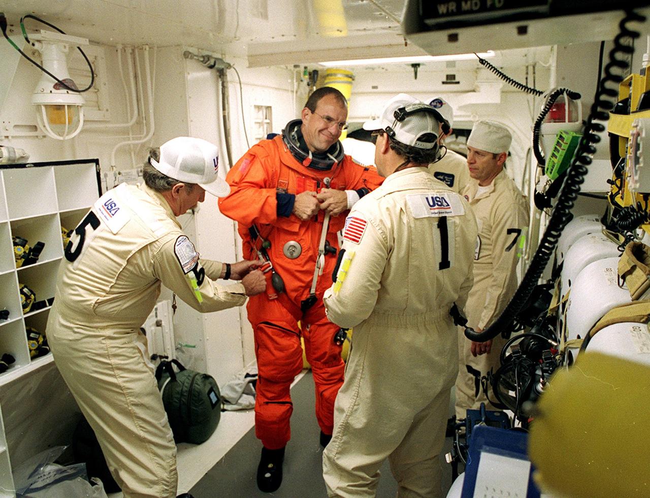 In the White Room, STS-97 Pilot Michael Bloomfield (center) prepares for entry into Space Shuttle Endeavour with the help of the Closeout Crew, (left to right) Al Schmidt, Travis Thompson and Mike Birkenseher. Space Shuttle Endeavour is targeted to launch Nov. 30 at 10:06 p.m. EST for the six construction flight to the International Space Station. Endeavour is transporting the P6 Integrated Truss Structure that comprises Solar Array Wing-3 and the Integrated Electronic Assembly, to provide power to the Space Station. After the 11-day mission, which includes three spacewalks, it is expected to land at KSC Dec. 11 at 6:19 p.m. EST