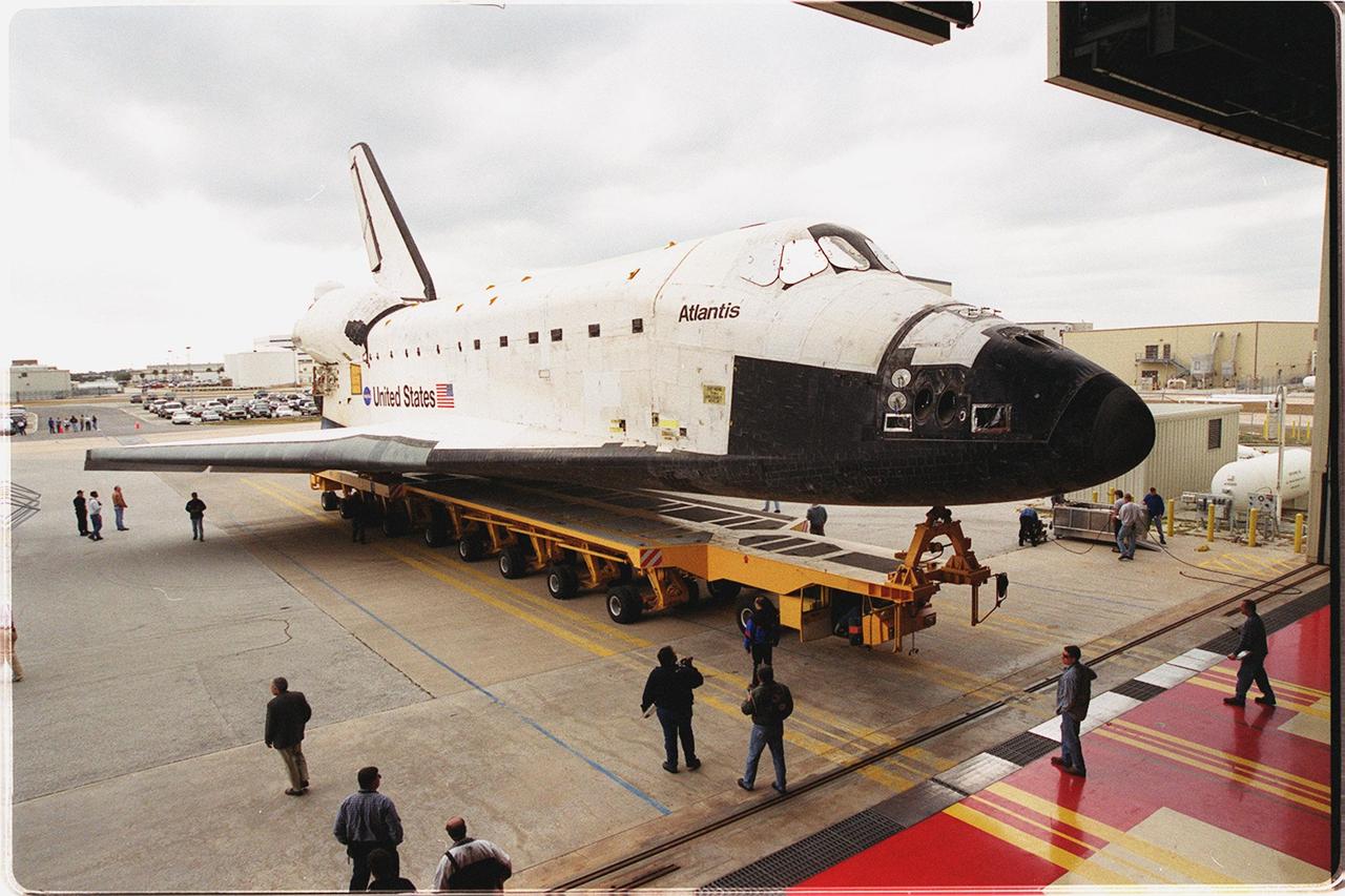 The orbiter Atlantis rolls out of the Orbiter Processing Facility bay 3 on its transporter. It is being transferred to the Vehicle Assembly Building where it will be raised to vertical and lifted up and into high bay 3 for stacking with its external tank and solid rocket boosters. Atlantis will fly on mission STS-98, the seventh construction flight to the International Space Station. The orbiter will carry in its payload bay the U.S. Laboratory, named Destiny, that will have five system racks already installed inside of the module. After delivery of electronics in the lab, electrically powered attitude control for Control Moment Gyroscopes will be activated. Atlantis is scheduled for launch on Jan. 18, 2001, at 2:44 a.m. EST, with a crew of five
