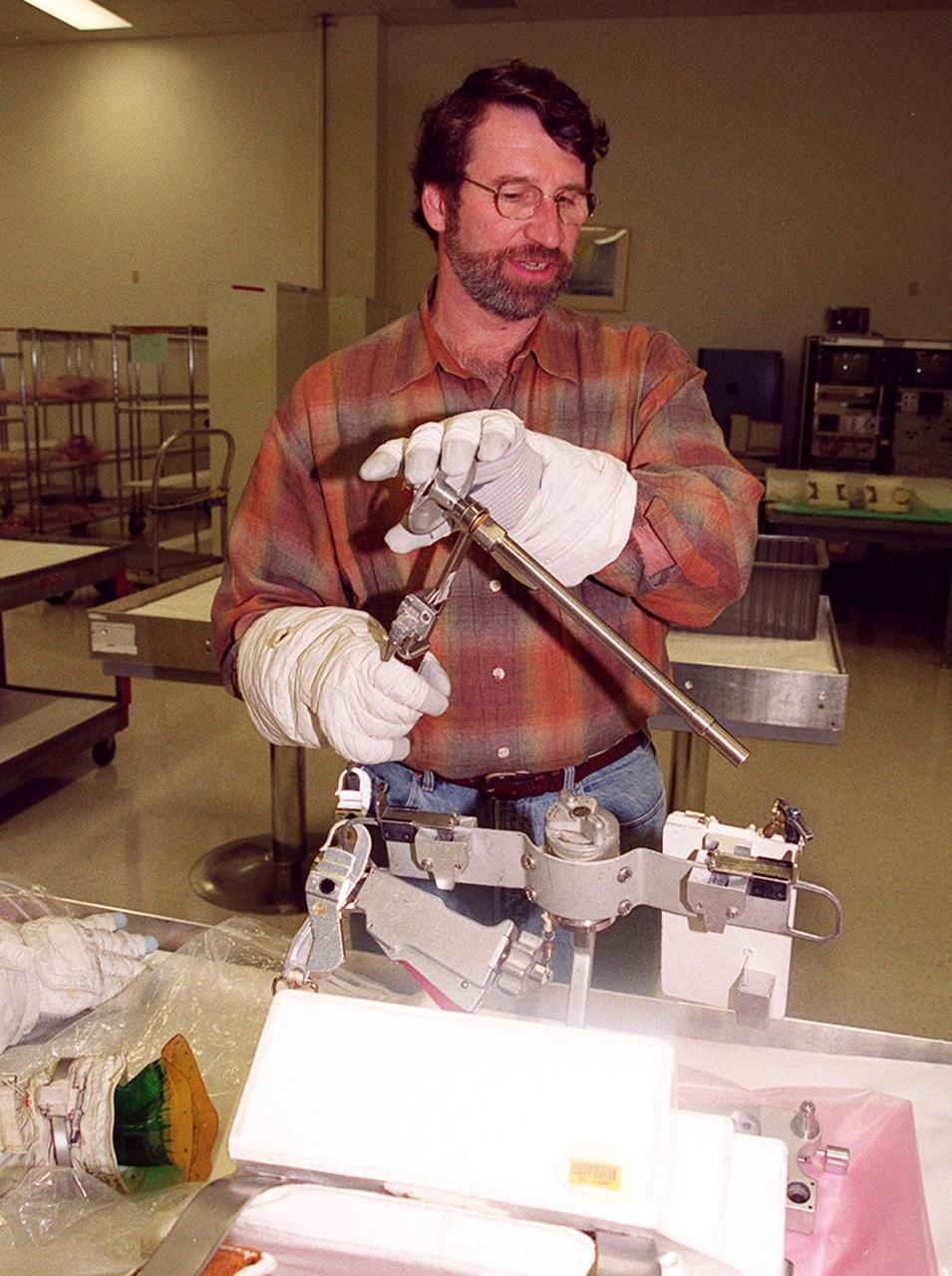KENNEDY SPACE CENTER, FLA. --  Norm Abram, master carpenter of television’s "This Old House" and "The New Yankee Workshop," tries out a tool used in space while wearing gloves that are part of the spacewalking suits. Abram is at KSC to film an episode of "This Old House.