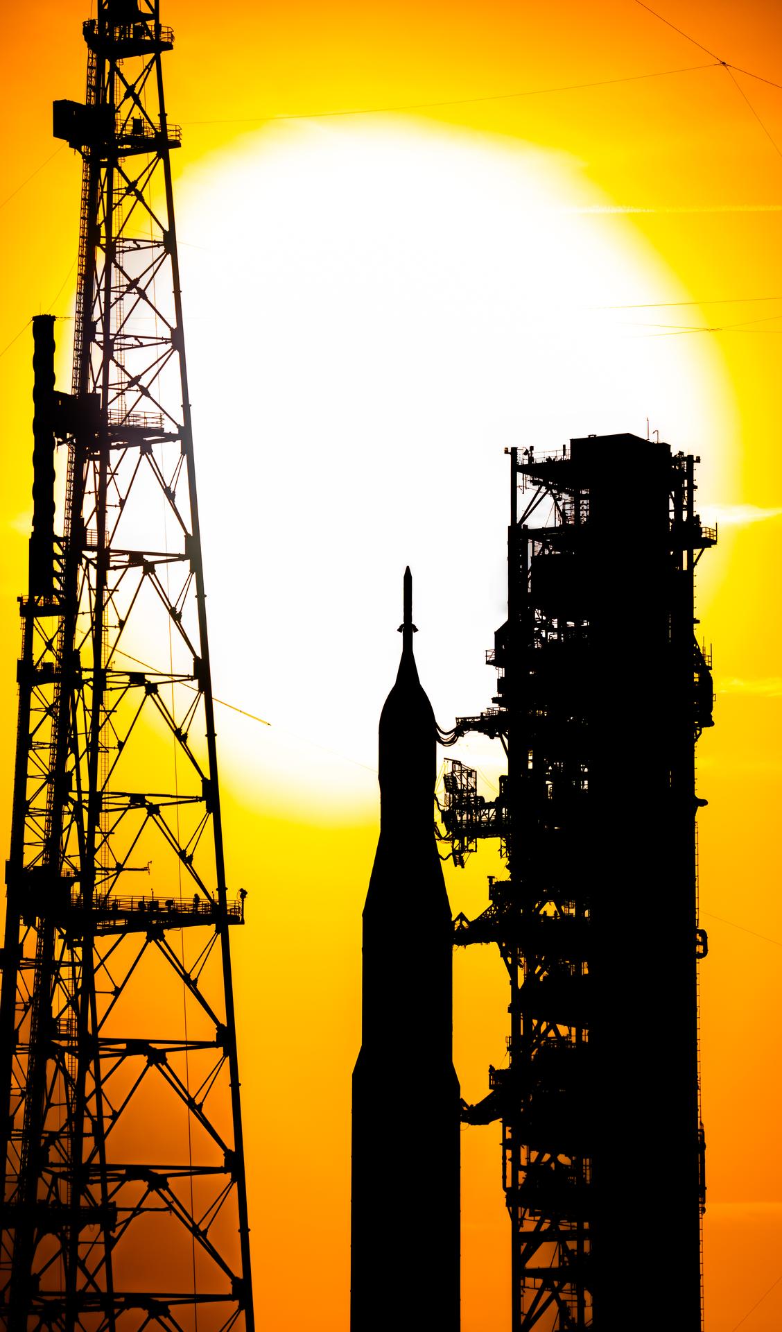 The sun sets as NASA’s crawler-transporter 2 carrying the agency’s Artemis II SLS (Space Launch System) rocket and Orion spacecraft, secured to the mobile launcher, rolls toward Launch Complex 39B at NASA’s Kennedy Space Center in Florida on 01/17/2026. The Artemis II test flight will take Commander Reid Wiseman, Pilot Victor Glover, and Mission Specialist Christina Koch from NASA and Mission Specialist Jeremy Hansen from the CSA (Canadian Space Agency), around the Moon and back to Earth no later than April 2026.
