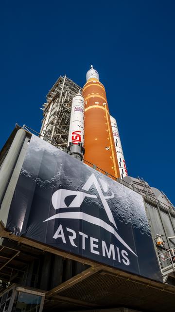 This image shows NASA’s SLS (Space Launch System) and Orion spacecraft rollin...