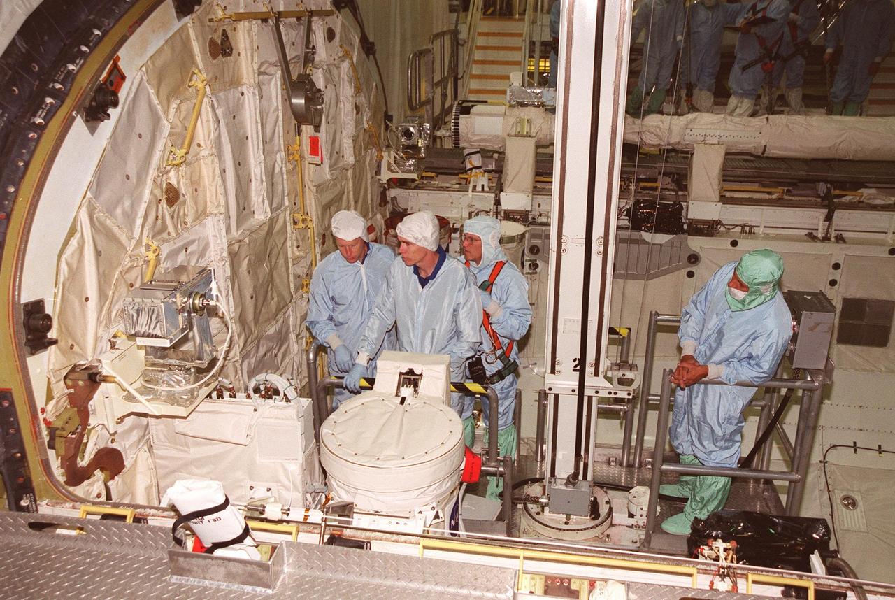 KENNEDY SPACE CENTER, FLA. -- During Crew Equipment Interface Test activities in Orbiter Processing Facility bay 2, members of the STS-105 crew check out some of the payload, doing sharp edge inspection. From left are Mission Specialists Patrick Forrester and Daniel Barry, accompanied by a Boeing technician (behind) and the bucket operator (right). STS-105 is the 11th mission to the International Space Station. The payload includes the Multi-Purpose Logistics Module Leonardo, which was built by the Italian Space Agency. Leonardo will be outfitted with 12 racks of experiments and equipment. Discovery is scheduled to launch July 12 from Launch Pad 39A