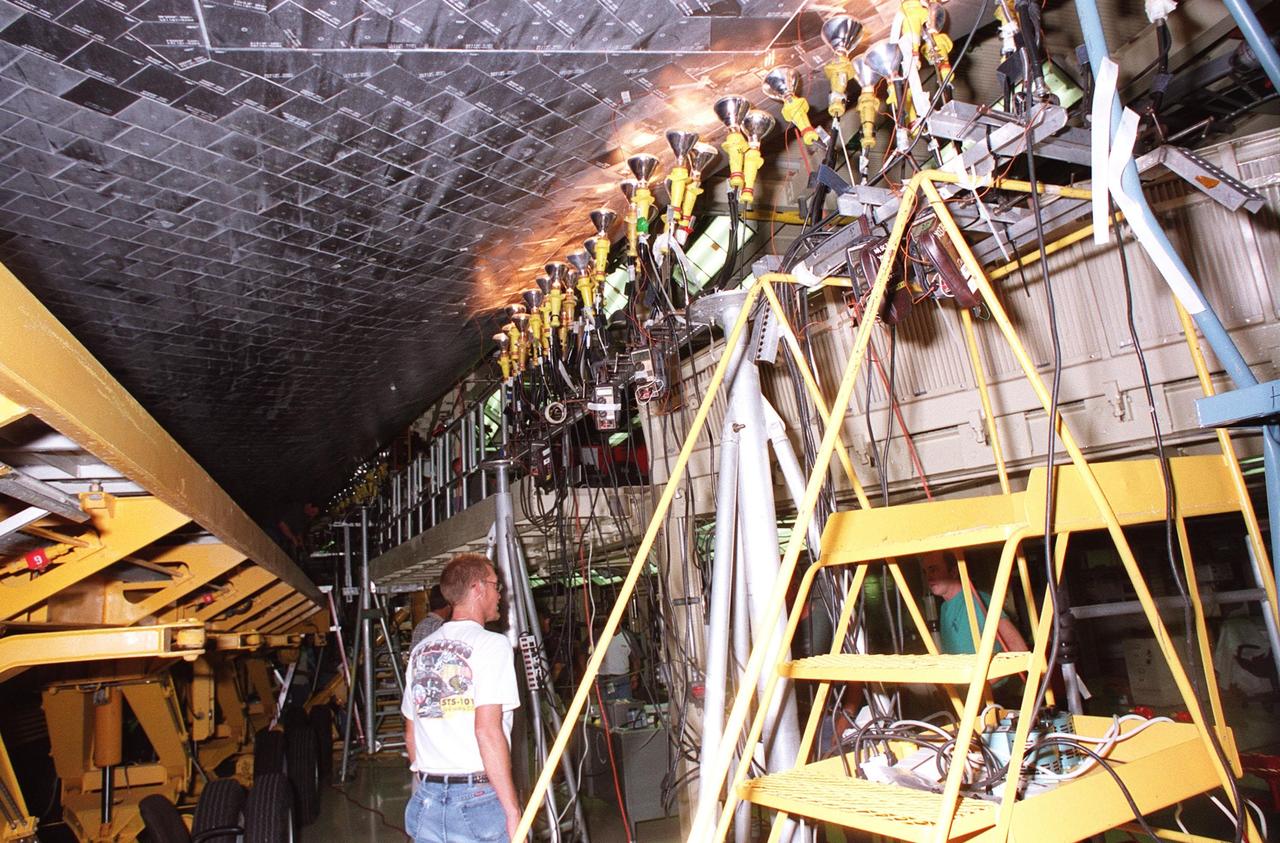 KENNEDY SPACE CENTER, FLA. -- In the Orbiter Processing Facility, a worker points to some of the tiles on orbiter Atlantis that are being dried by clusters of 200-300 watt heat lamps. Significant rainstorms during the orbiter’s turnaround for a ferry flight home from Edwards Air Force Base, Calif., caused a moisture problem. The tiles are part of the Thermal Protection System used on orbiters for extreme temperatures encountered during landing. Engineers are evaluating the current procedures to assure the tiles are in a safe and flight-ready condition