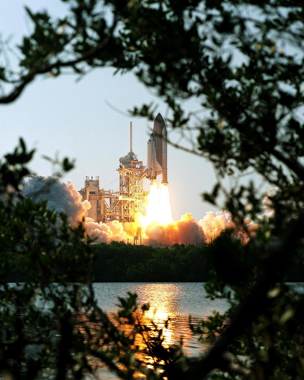 KENNEDY SPACE CENTER, Fla. -- Trees frame Space Shuttle Discovery trailing columns of fire from the solid rocket boosters as it soars into the blue sky on mission STS-105 to the International Space Station. Liftoff from Launch Pad 39A occurred at 5:10:14 p.m. EDT. Besides the Shuttle crew of four, Discovery carries the Expedition Three crew who will replace Expedition Two on the Space Station. The mission payload includes the third flight of the Italian-built Multi-Purpose Logistics Module Leonardo, delivering additional scientific racks, equipment and supplies for the Space Station, and the Early Ammonia Servicer (EAS) tank. The EAS, which will be attached to the Station during two spacewalks, contains spare ammonia for the Station’s cooling system. The three-member Expedition Two crew will be returning to Earth aboard Discovery after a five-month stay on the Station