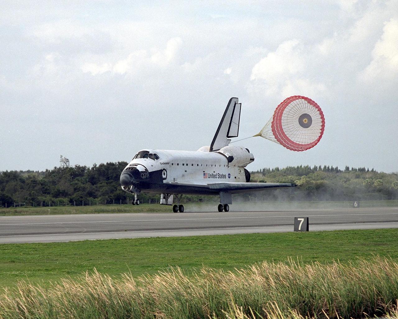 KENNEDY SPACE CENTER, FLA. --  With its drag chute billowing behind, orbiter Endeavour slows for a full touchdown on Runway 15 at the KSC Shuttle Landing Facility, completing mission STS-108. Endeavour carries both the mission crew and the Expedition 3 crew - Commander Frank Culbertson and cosmonauts Vladimir Dezhurov and Mikhail Tyurin - who are returning to Earth after 129 days in space on the International Space Station.  After a mission-elapsed time of 11 days, 19 hours and 35 minutes, Endeavour had main gear touchdown at 12:55:10 p.m. EST (17:55:10 GMT).  Nose gear touchdown occurred at 12:55:23 p.m. (17:55:23 GMT); wheel stop at 12:56:13 p.m. (17:56:13 GMT). Rollout distance was 8,941 feet.  The landing is the 57th at KSC in the history of the program   STS-108 was the 12th mission to the Space Station.  This mission was the 107th flight in the Shuttle program and the 17th flight for the orbiter
