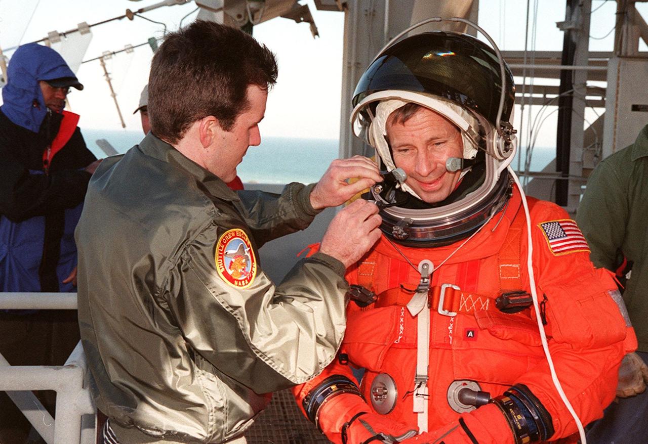 During emergency egress training at the Launch Pad, Commander Ken Cockrell gets help adjusting his helmet. The crew is practicing using the slidewire baskets that slide along 1200-foot wire to the landing zone below and nearby bunker. The crew has been taking part in Terminal Countdown Demonstration Test activities, which include the simulated countdown and emergency egress training at the pad. STS-98 is the seventh construction flight to the International Space Station, carrying as payload the U.S. Lab Destiny, a key element in the construction of the ISS. Launch of STS-98 is scheduled for Jan. 19 at 2:11 a.m. EST