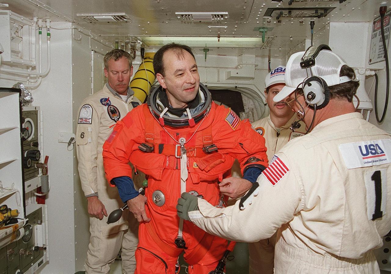 In the White Room, STS-98 Pilot Mark Polansky gets help with his launch and entry suit before entering Atlantis for a simulated launch countdown. The White Room is an environmental chamber at the end of the orbiter access arm that mates with the orbiter to allow personnel to enter the orbiter’s crew compartment. The STS-98 crew is taking part in Terminal Countdown Demonstration Test activities, which also include emergency egress training at the pad. STS-98 is the seventh construction flight to the International Space Station, carrying as payload the U.S. Lab Destiny, a key element in the construction of the ISS. Launch of STS-98 is scheduled for Jan. 19 at 2:11 a.m. EST