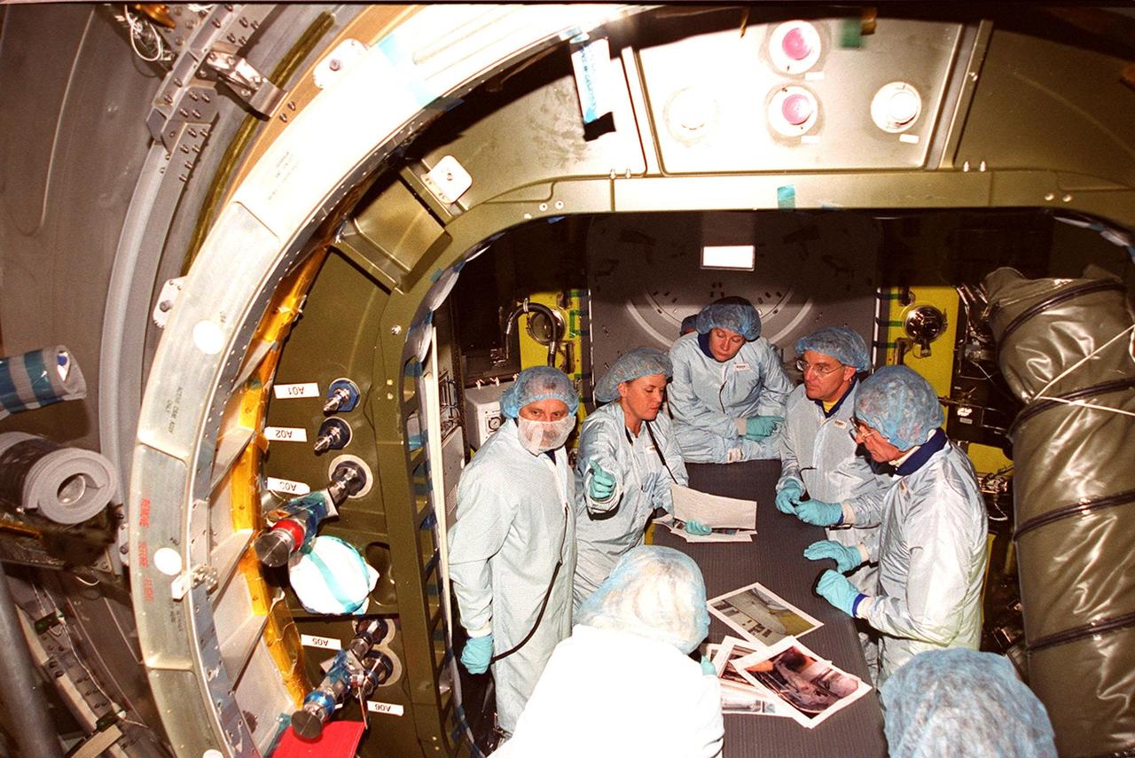 At the Space Station Processing Facility, the Expedition Two crew check out the inside of the air lock. Cosmonaut Yury Usachev is at left; astronaut Susan Helms is seated, center; and astronaut James Voss is second from right. They are joined by astronaut John Young, at right, who flew on mission STS-1. Voss, Helms and Usachev will be flying on mission STS-102, launching March 8, to the International Space Station. The air lock will be carried to the Station during their tenure in space. STS-102 will be Helms’ and Voss’s fifth Shuttle flight, and Usachev’s second. They will be replacing the Expedition One crew (Bill Shepherd, Yuri Gidzenko and Sergei Krikalev), who will return to Earth March 20 on Discovery along with the STS-102 crew