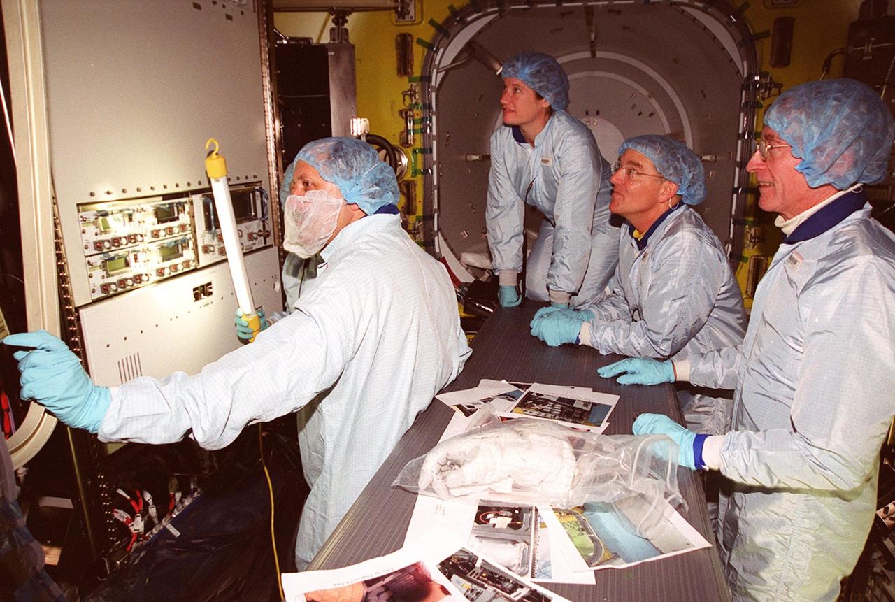 Inside the air lock in the Space Station Processing Facility, the Expedition Two crew look at equipment. Seen from left are cosmonaut Yury Usachev and astronauts Susan Helms and James Voss. At far right is astronaut John Young, who flew on mission STS-1. Usachev, Helms and Voss will be flying on mission STS-102, launching March 8. The air lock will be carried to the Station during their tenure in space. STS-102 will be Helms’ and Voss’s fifth Shuttle flight, and Usachev’s second. They will be replacing the Expedition One crew (Bill Shepherd, Yuri Gidzenko and Sergei Krikalev), who will return to Earth March 20 on Discovery along with the STS-102 crew
