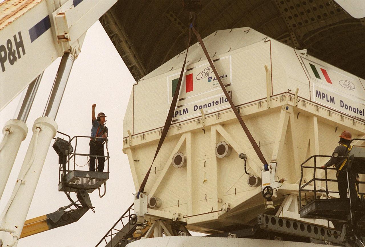 At the <a href="../../subjects/slf.htm"> Shuttle Landing Facility</a>, workers in cherry pickers (left and right) help direct the offloading of the Italian Space Agency’s <a href="../../subjects/mplm.htm"> Multi-Purpose Logistics Module</a> Donatello from the Airbus “Beluga” air cargo plane that brought it from the factory of Alenia Aerospazio in Turin, Italy. The third of three for the International Space Station, the module will be transported to the <a href="../../subjects/sspf.htm"> Space Station Processing Facility</a> for processing. Among the activities for the payload test team are integrated electrical tests with other Station elements in the SSPF, leak tests, electrical and software compatibility tests with the Space Shuttle (using the Cargo Integrated Test equipment) and an Interface Verification Test once the module is installed in the Space Shuttle’s payload bay at the launch pad. The most significant mechanical task to be performed on Donatello in the SSPF is the installation and outfitting of the racks for carrying the various experiments and cargo