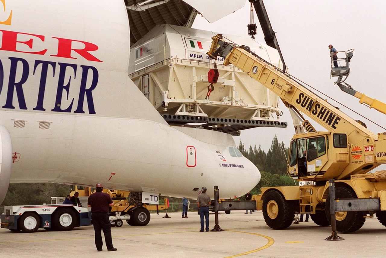 At the Shuttle Landing Facility, workers in cherry pickers (right) help guide offloading of the Italian Space Agency’s Multi-Purpose Logistics Module Donatello from the Airbus “Beluga” air cargo plane that brought it from the factory of Alenia Aerospazio in Turin, Italy. The third of three for the International Space Station, the module will be transported to the Space Station Processing Facility for processing. Among the activities for the payload test team are integrated electrical tests with other Station elements in the SSPF, leak tests, electrical and software compatibility tests with the Space Shuttle (using the Cargo Integrated Test equipment) and an Interface Verification Test once the module is installed in the Space Shuttle’s payload bay at the launch pad. The most significant mechanical task to be performed on Donatello in the SSPF is the installation and outfitting of the racks for carrying the various experiments and cargo