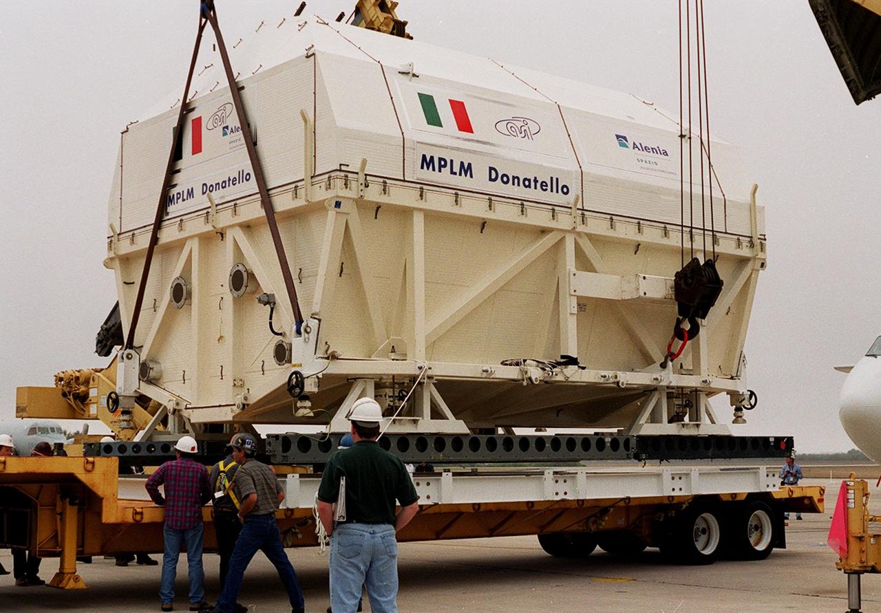 At the Shuttle Landing Facility, workers watch as cranes lower the Italian Space Agency’s Multi-Purpose Logistics Module Donatello onto a flat bed for transport to the Space Station Processing Facility for processing. Among the activities for the payload test team are integrated electrical tests with other Station elements in the SSPF, leak tests, electrical and software compatibility tests with the Space Shuttle (using the Cargo Integrated Test equipment) and an Interface Verification Test once the module is installed in the Space Shuttle’s payload bay at the launch pad. The most significant mechanical task to be performed on Donatello in the SSPF is the installation and outfitting of the racks for carrying the various experiments and cargo