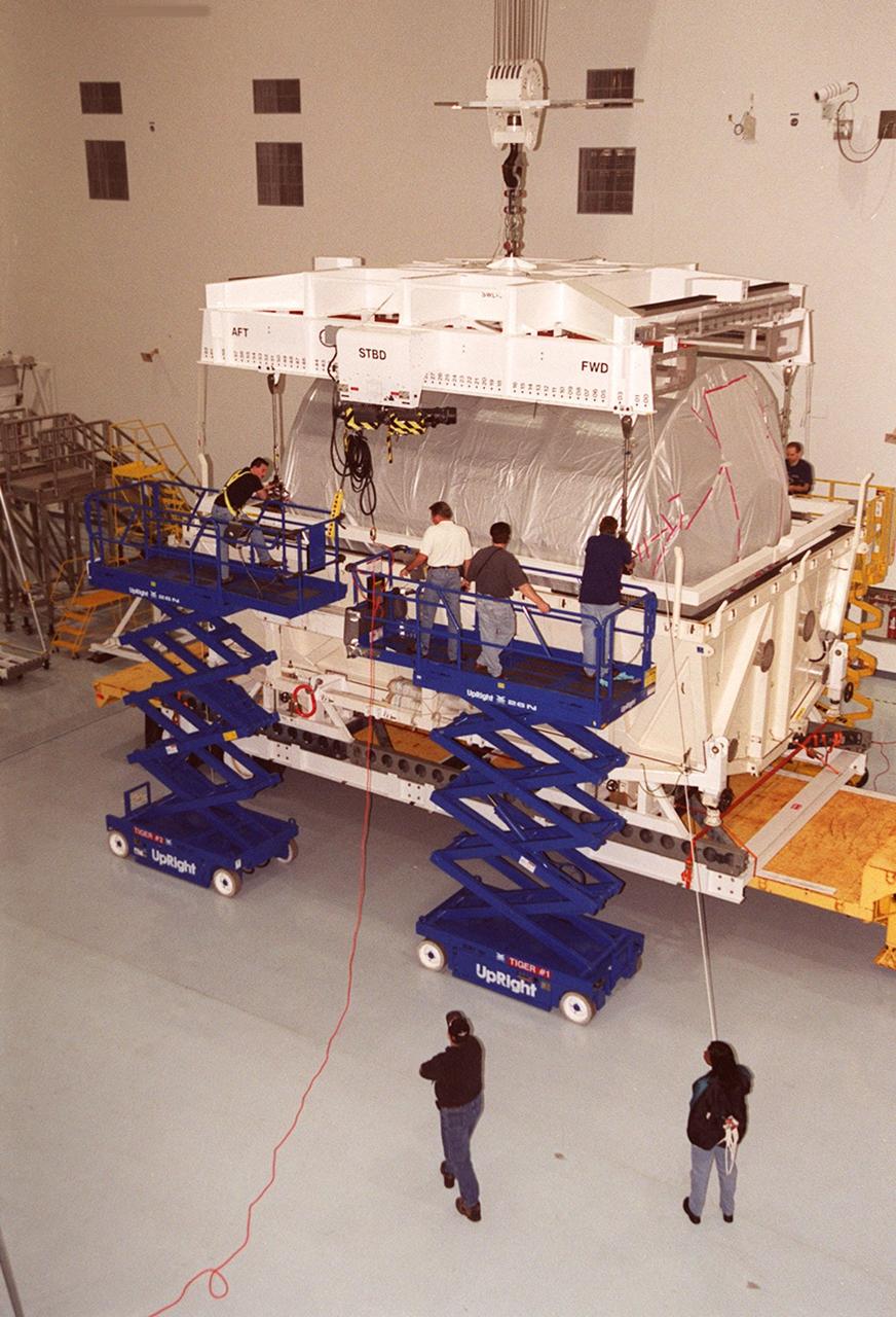 Workers in the Space Station Processing Facility attach an overhead crane to the Multi-Purpose Logistics Module Donatello to lift it out of the shipping container. In the SSPF, Donatello will undergo processing by the payload test team, including integrated electrical tests with other Station elements in the SSPF, leak tests, electrical and software compatibility tests with the Space Shuttle (using the Cargo Integrated Test equipment) and an Interface Verification Test once the module is installed in the Space Shuttle’s payload bay at the launch pad. The most significant mechanical task to be performed on Donatello in the SSPF is the installation and outfitting of the racks for carrying the various experiments and cargo. Donatello will be launched on mission STS-130, currently planned for September 2004