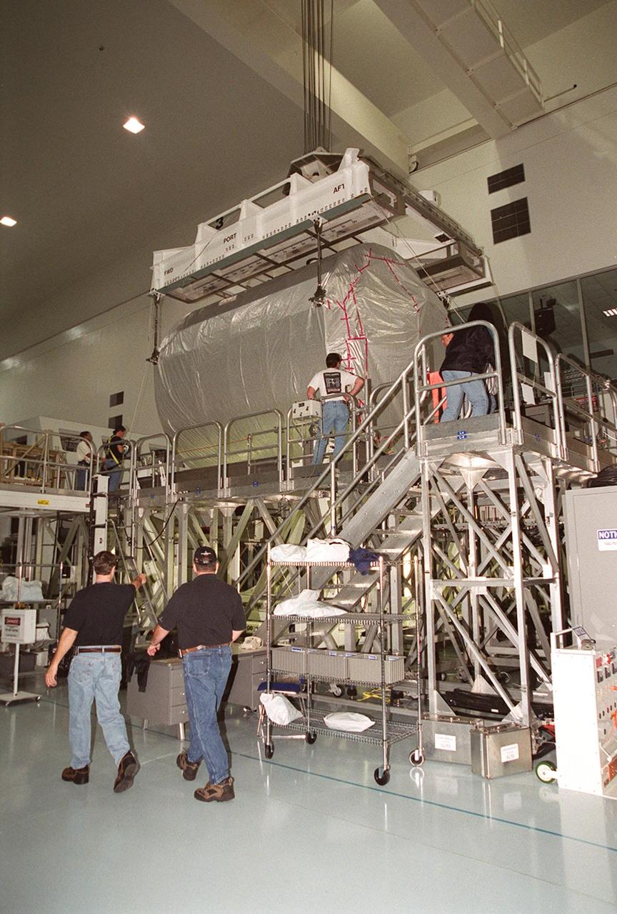 An overhead crane lowers the Multi-Purpose Logistics Module Donatello onto a workstand. In the SSPF, Donatello will undergo processing by the payload test team, including integrated electrical tests with other Station elements in the SSPF, leak tests, electrical and software compatibility tests with the Space Shuttle (using the Cargo Integrated Test equipment) and an Interface Verification Test once the module is installed in the Space Shuttle’s payload bay at the launch pad. The most significant mechanical task to be performed on Donatello in the SSPF is the installation and outfitting of the racks for carrying the various experiments and cargo. Donatello will be launched on mission STS-130, currently planned for September 2004