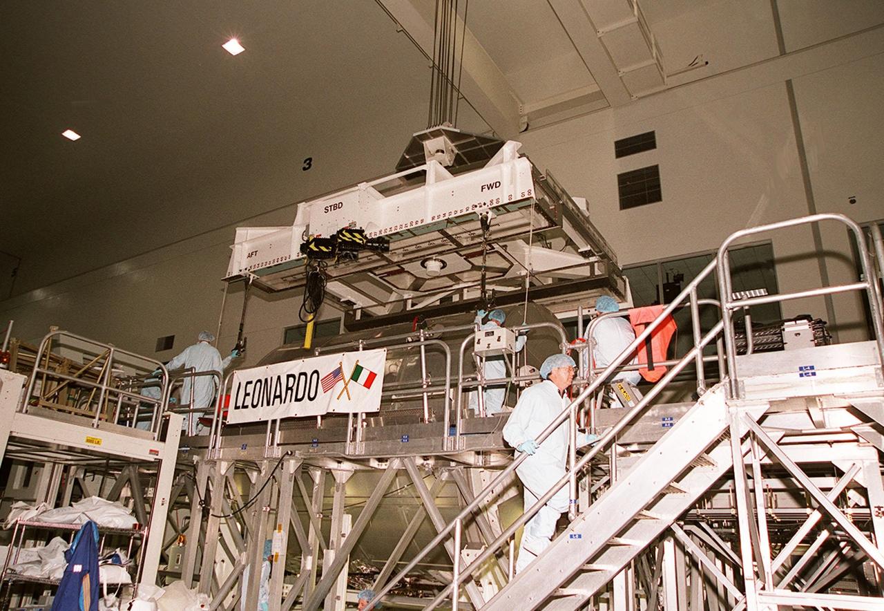 On a workstand in the Space Station Processing Facility, workers stand by while an overhead crane is ready to lift the Multi-Purpose Logistics Module Leonardo to move it to the weight and balance scale. The Italian-built MPLM is one of three such pressurized modules that will serve as the International Space Station's "moving vans," carrying laboratory racks filled with equipment, experiments and supplies to and from the station aboard the Space Shuttle. The cylindrical module is approximately 21 feet long and 15 feet in diameter, weighing almost 4.1 metric tons. It can carry up to 9.1 metric tons of cargo packed into 16 standard space station equipment racks. The Leonardo will be launched on mission STS-102 March 8. On that flight, Leonardo will be filled with equipment and supplies to outfit the U.S. laboratory module, to be carried to the ISS on the Feb. 7 launch of STS-98