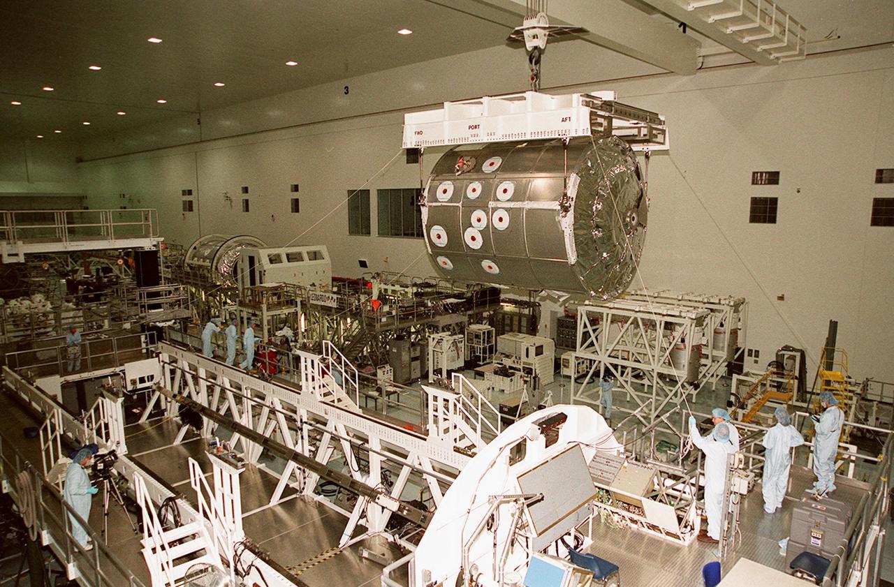 In the Space Station Processing Facility, workers help guide the Multi-Purpose Logistics Module Leonardo as it moves toward the weight and balance scale. The Italian-built MPLM is one of three such pressurized modules that will serve as the International Space Station's "moving vans," carrying laboratory racks filled with equipment, experiments and supplies to and from the station aboard the Space Shuttle. The cylindrical module is approximately 21 feet long and 15 feet in diameter, weighing almost 4.1 metric tons. It can carry up to 9.1 metric tons of cargo packed into 16 standard space station equipment racks. The Leonardo will be launched on mission STS-102 March 8. On that flight, Leonardo will be filled with equipment and supplies to outfit the U.S. laboratory module, to be carried to the ISS on the Feb. 7 launch of STS-98