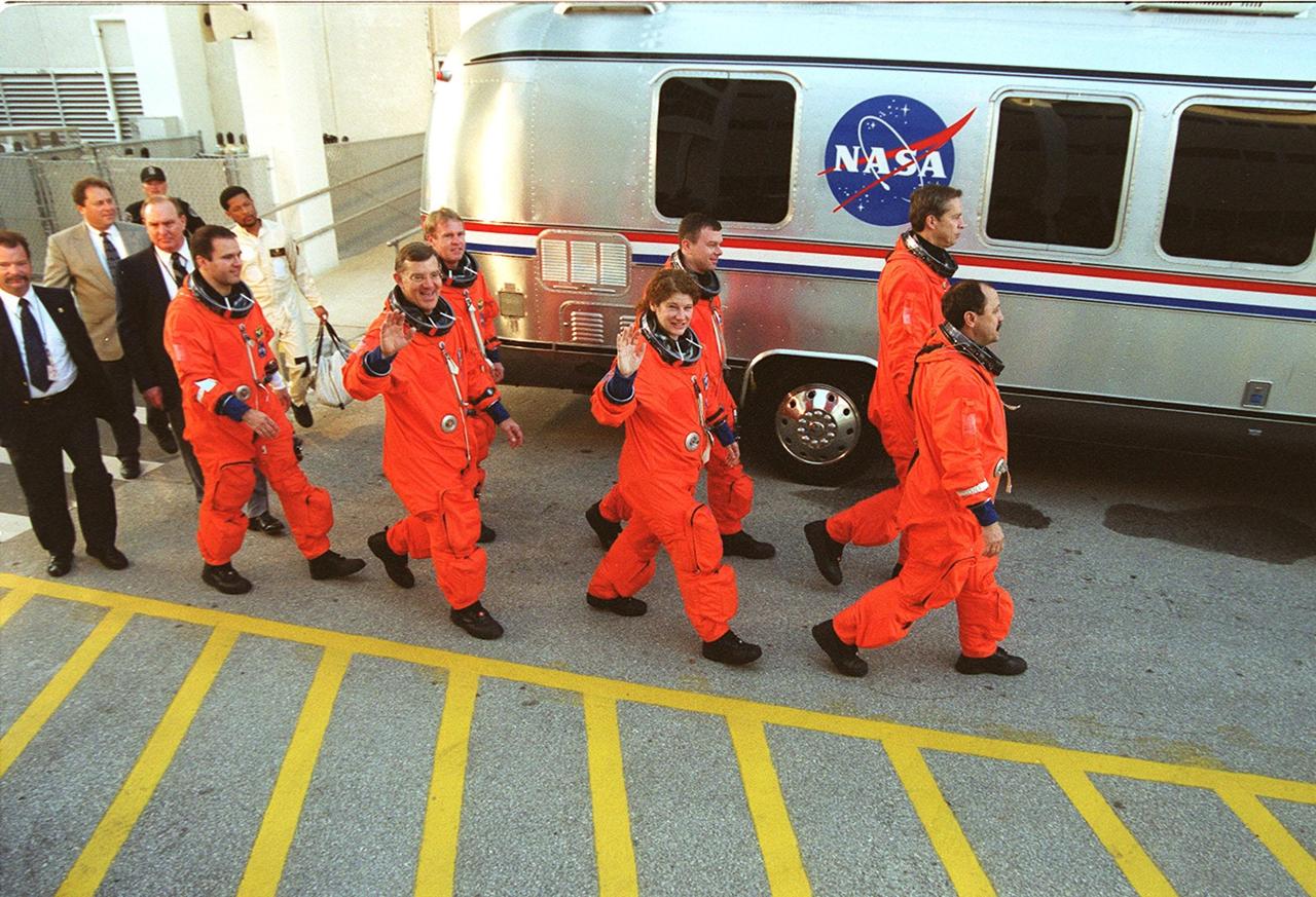 Waving to media and bystanders, the STS-102 crew strides to the silver Astrovan after leaving the Operations and Checkout Building. In front, left to right, are Mission Specialists Paul Richards, James Voss, Susan Helms and Yury Usachev. Behind then are Mission Specialist Andrew Thomas, Pilot James Kelly and Commander James Wetherbee. Voss, Helms and Usachev are the Expedition Two crew, going to the International Space Station for their four-month rotation. The Astrovan will take the crew to Launch Pad 39B for a simulated countdown, part of Terminal Countdown Demonstration Test activities. STS-102 is the eighth construction flight to the Space Station, with Space Shuttle Discovery carrying the Multi-Purpose Logistics Module Leonardo. In addition, Expedition One will return to Earth with Discovery. Launch on mission STS-102 is scheduled for March 8