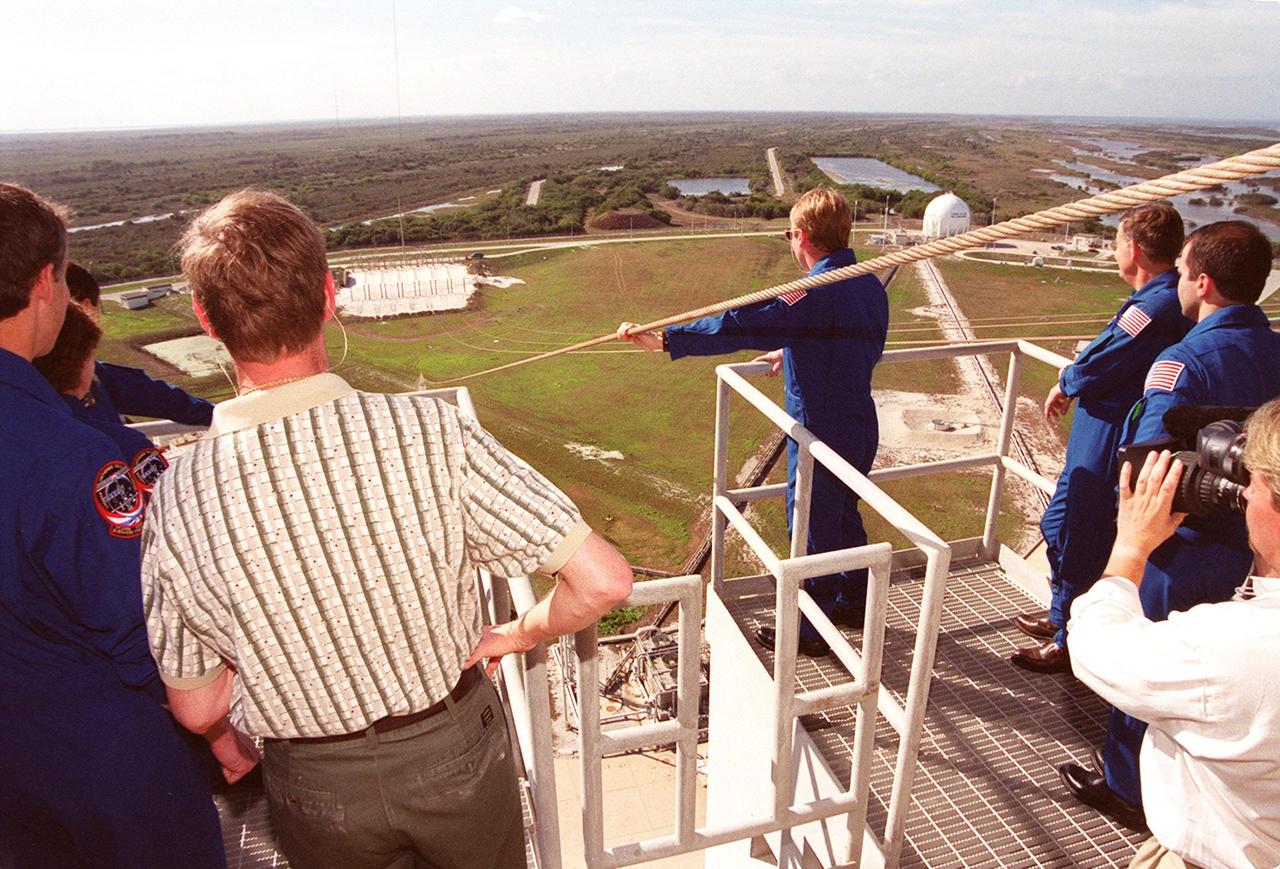 The STS-102 crew watches a slidewire basket speed down the line to the landing area. At left (backs to camera, back to front) are Commander James Wetherbee, Mission Specialists Susan Helms and Paul Richards. At right are (left to right) Mission Specialists Andrew Thomas and James Voss and Pilot James Kelly. Not seen is Mission Specialist Yury Usachev. The crew is taking part in Terminal Countdown Demonstration Test activities, which include the emergency exit training and a simulated launch countdown. STS-102 is the eighth construction flight to the International Space Station, with Space Shuttle Discovery carrying the Multi-Purpose Logistics Module Leonardo. Launch on mission STS-102 is scheduled for March 8